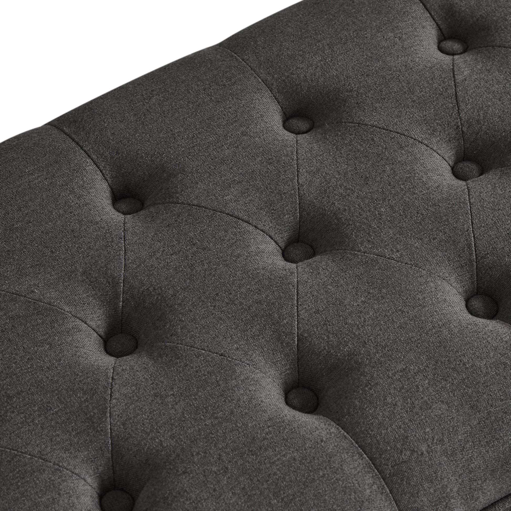 Dark grey tufted fabric ottoman detail with button accents