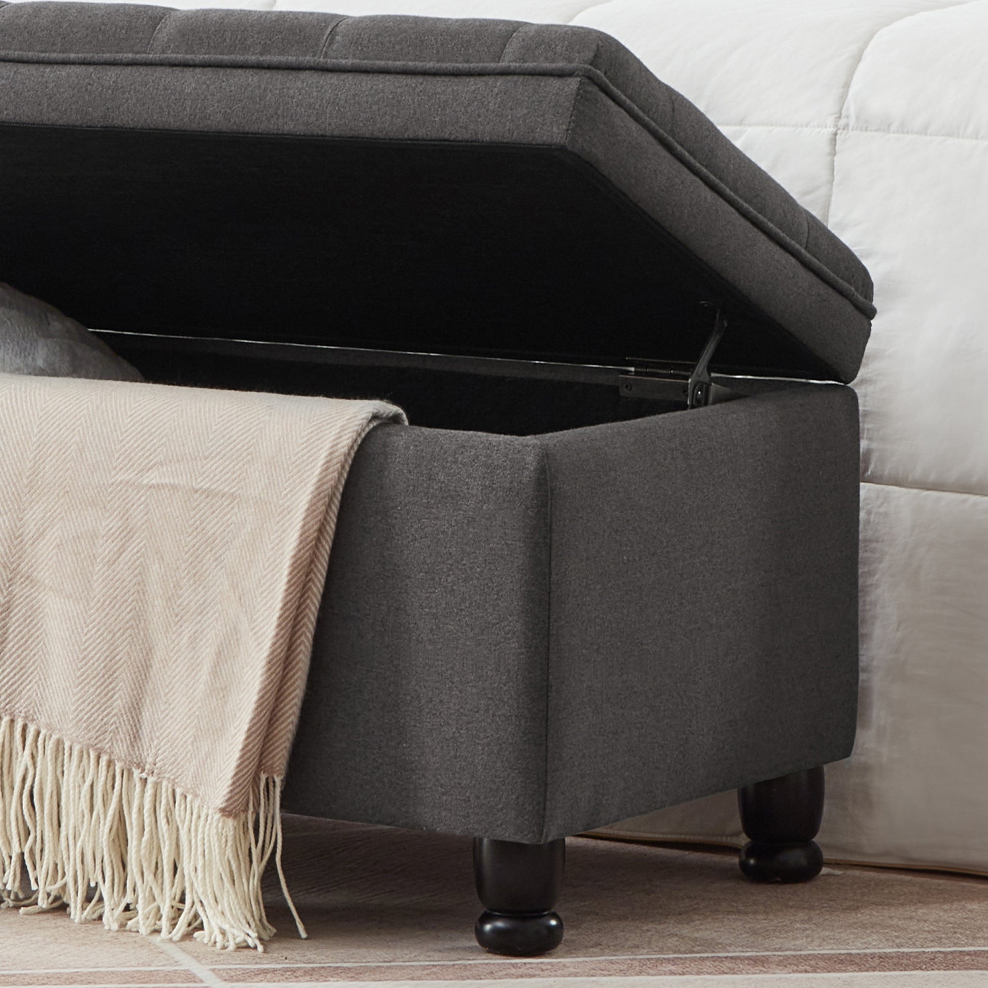 Dark grey tufted storage ottoman with beige throw blanket