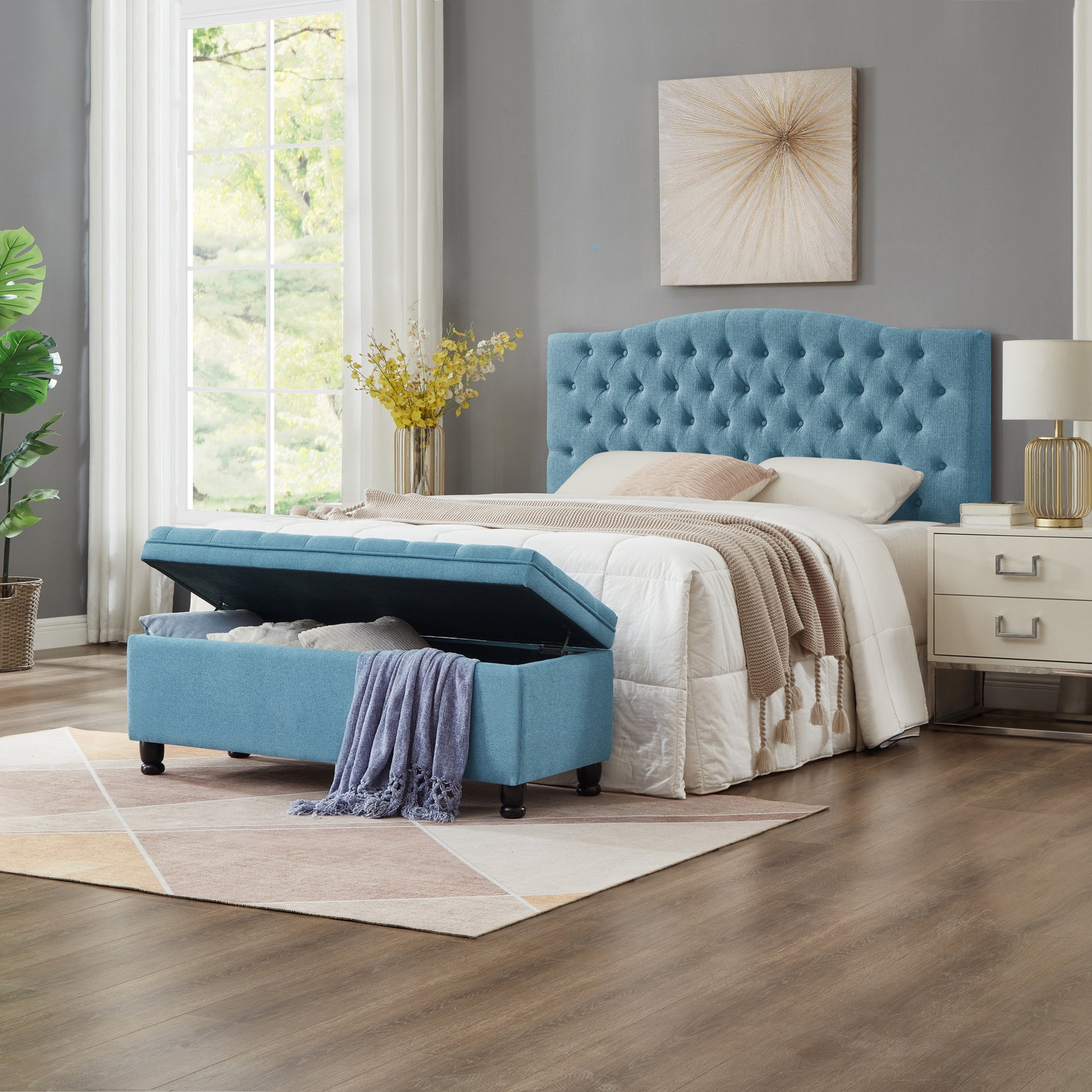 Blue tufted storage ottoman in upholstered fabric with open lid and blankets