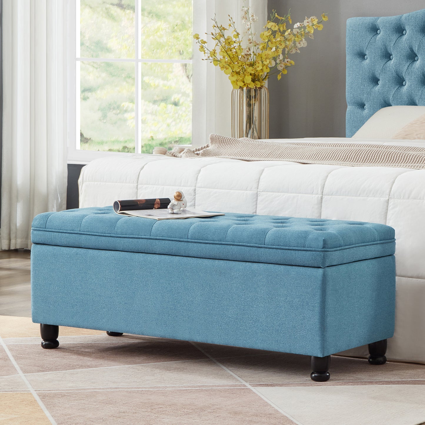Tufted blue storage ottoman with dark wood legs a stylish bedroom accent