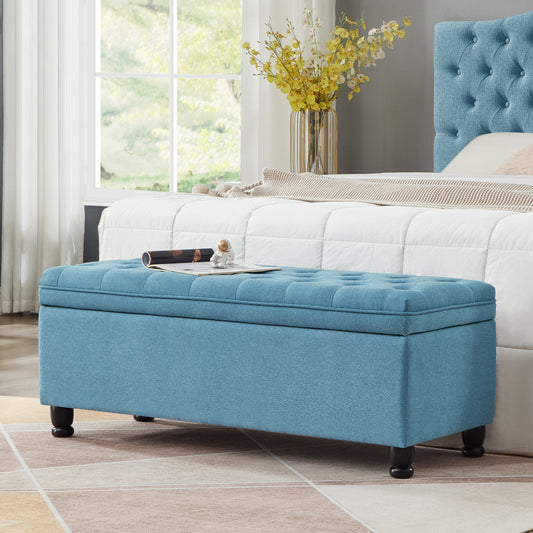 Tufted blue storage ottoman with dark wood legs a stylish bedroom accent