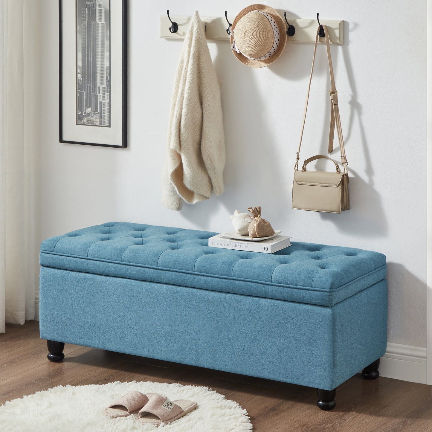 Blue tufted storage ottoman with dark wooden legs perfect for entryway or bedroom storage