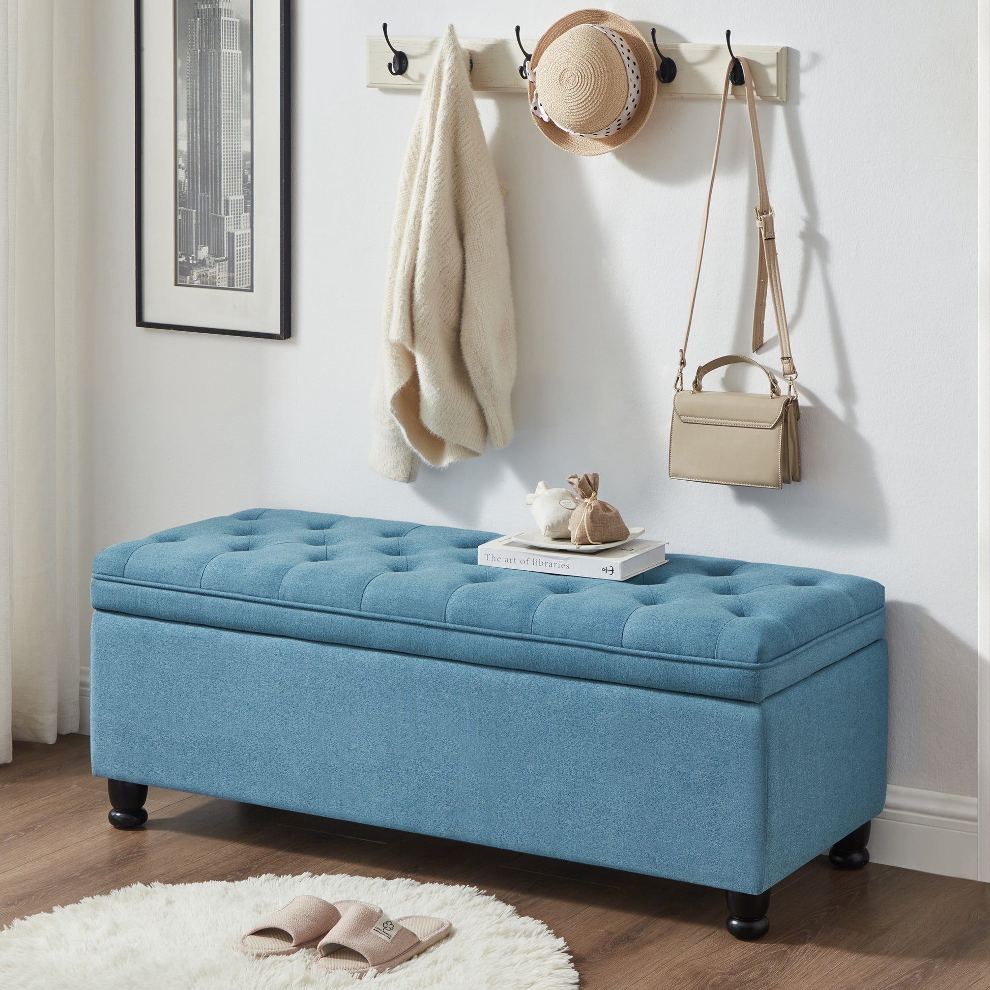 Blue tufted storage ottoman with dark wooden legs perfect for entryway or bedroom storage