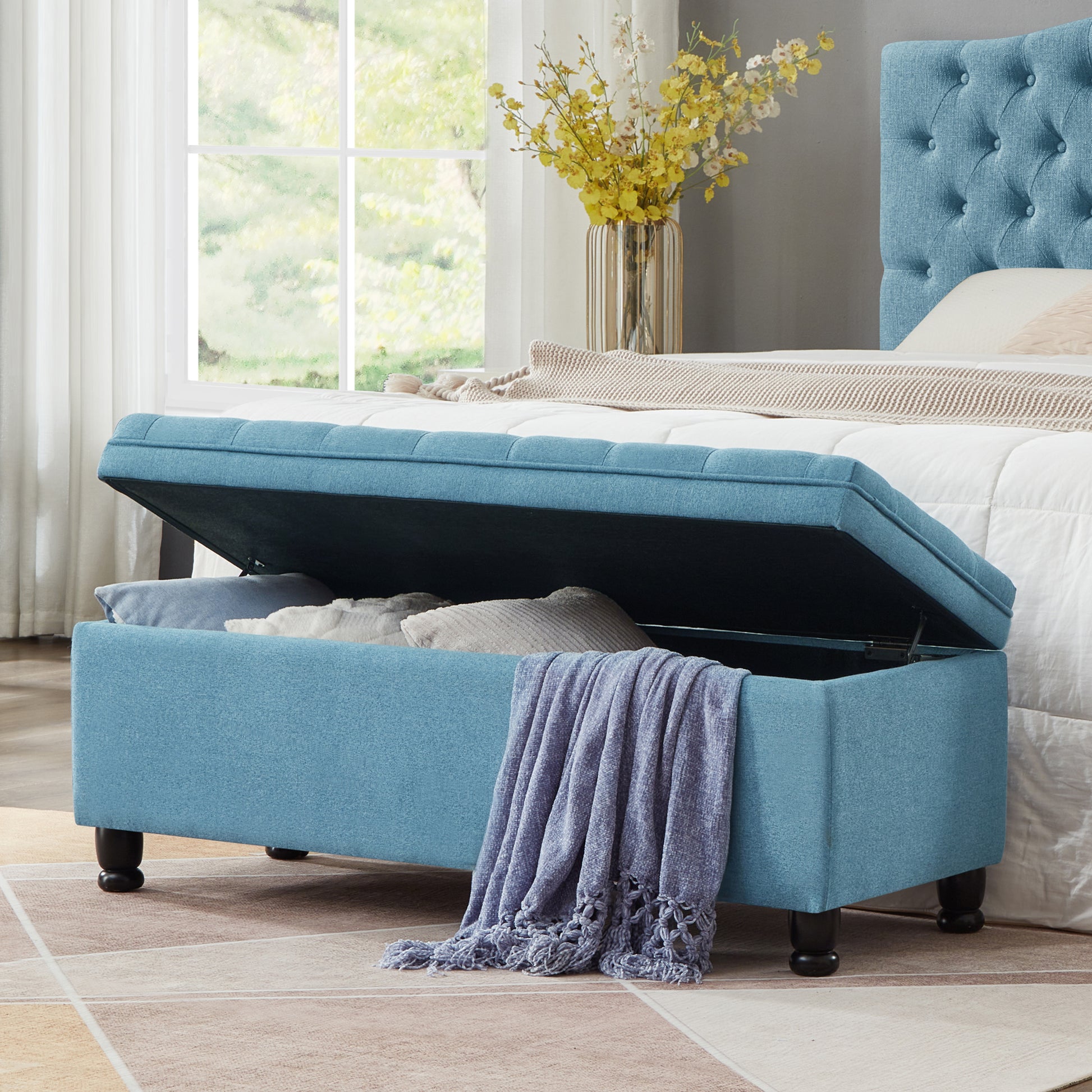 Blue upholstered storage ottoman with tufted lid and ample interior storage