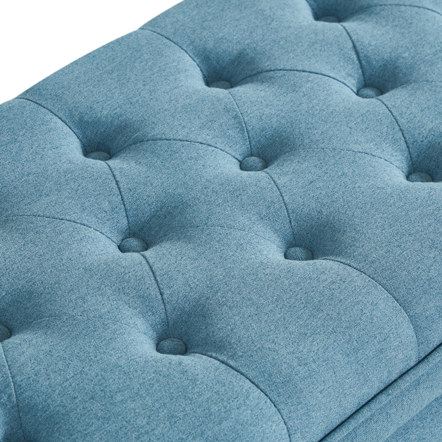 Closeup of tufted light blue fabric upholstery with button details on a bench