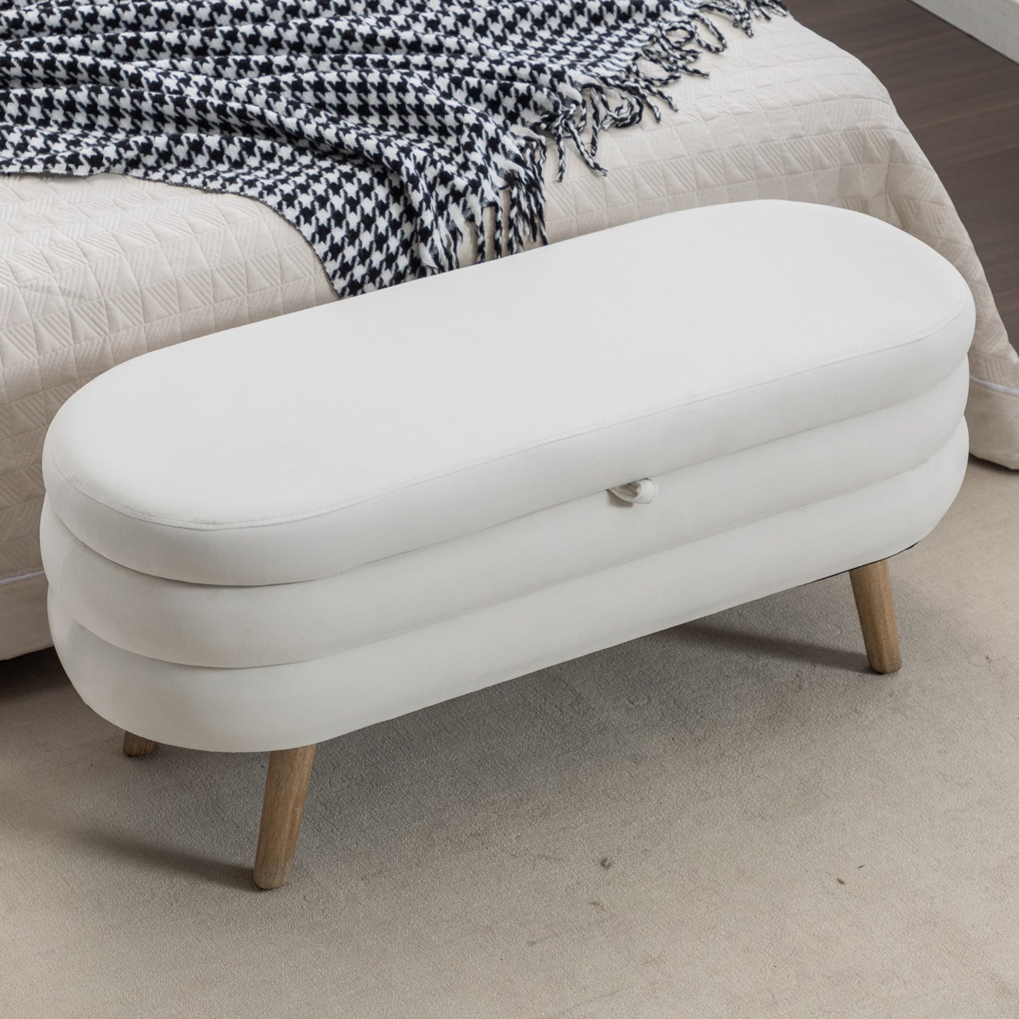 White upholstered storage ottoman with wooden legs and tufted detailing