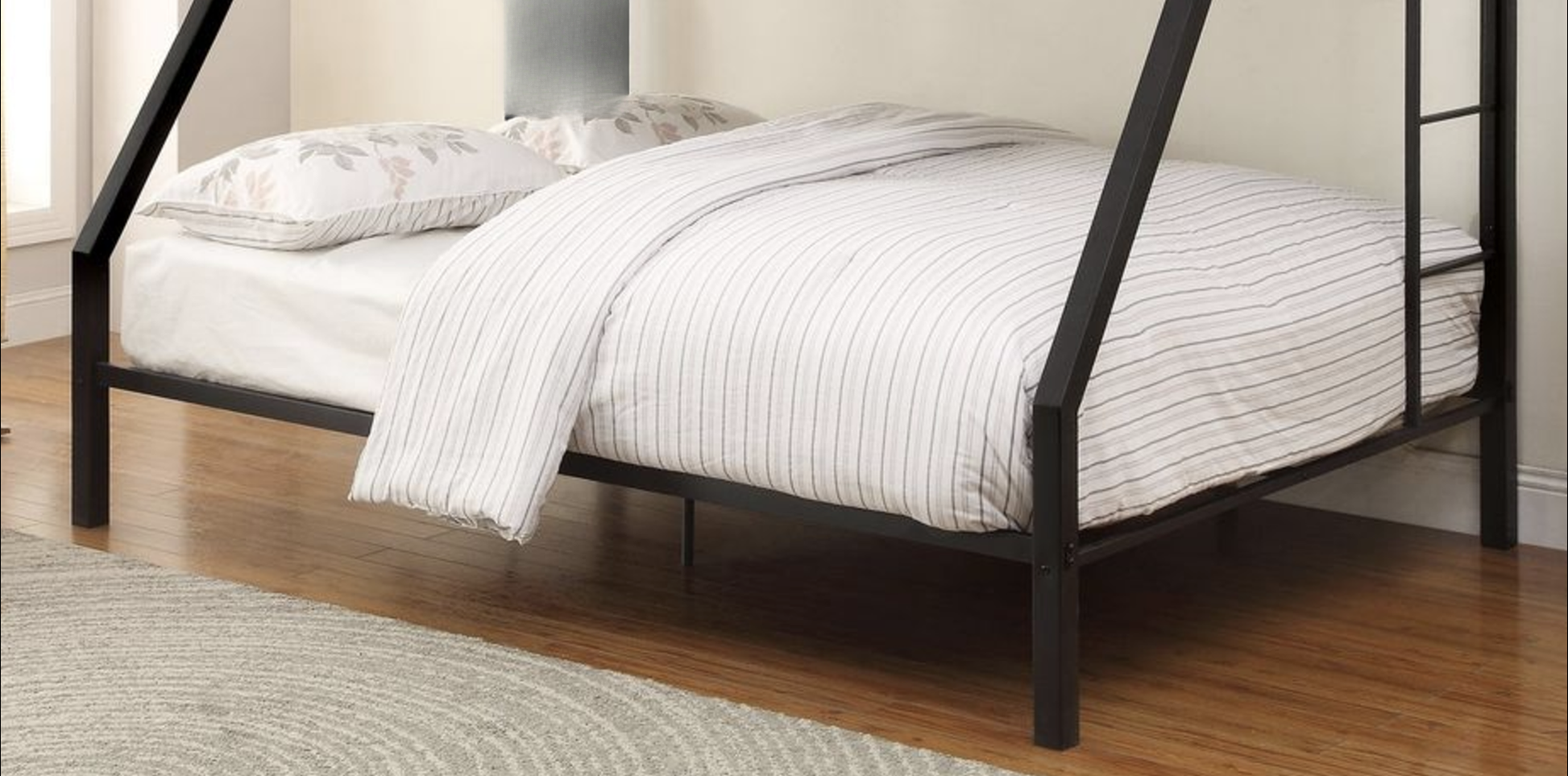 Black metal bunk bed frame with white striped bedding and floral pillows