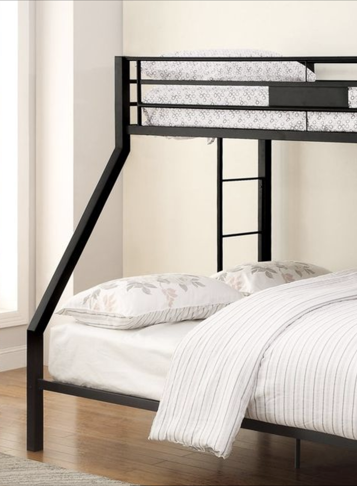 Black metal twin over twin bunk bed with white striped bedding and floral pillows