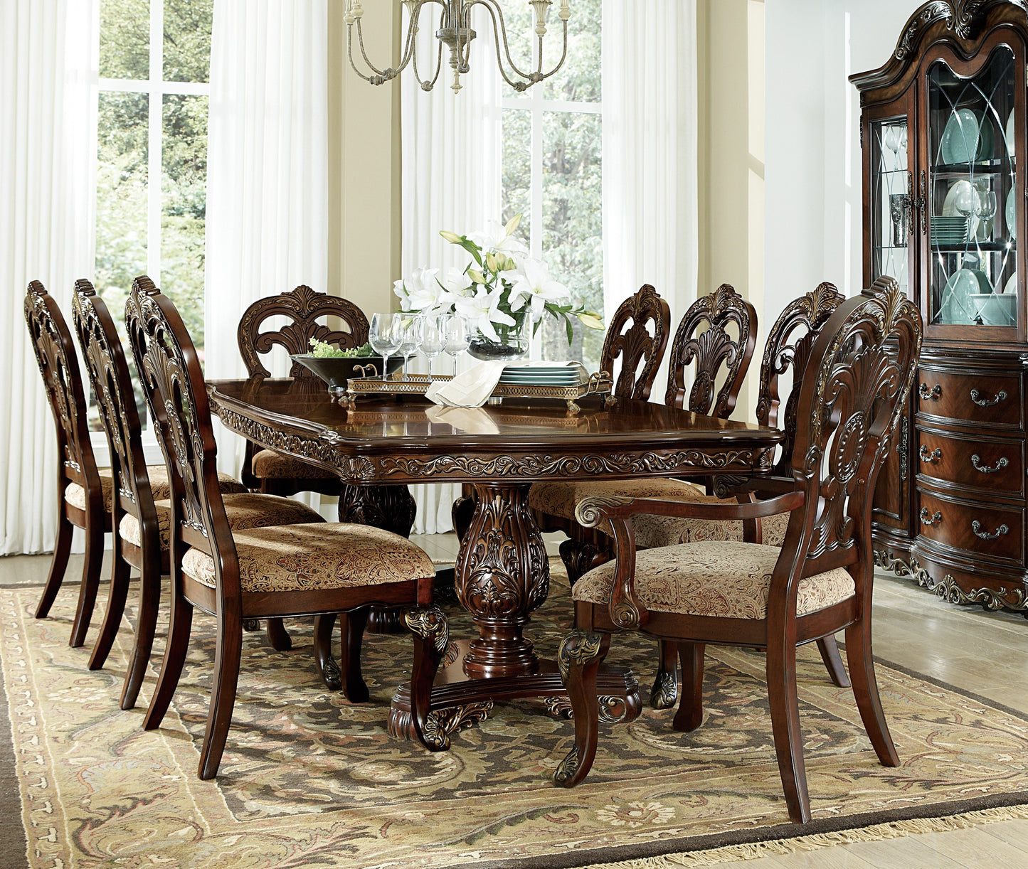 Ornate dark wood dining table with upholstered chairs and a china cabinet