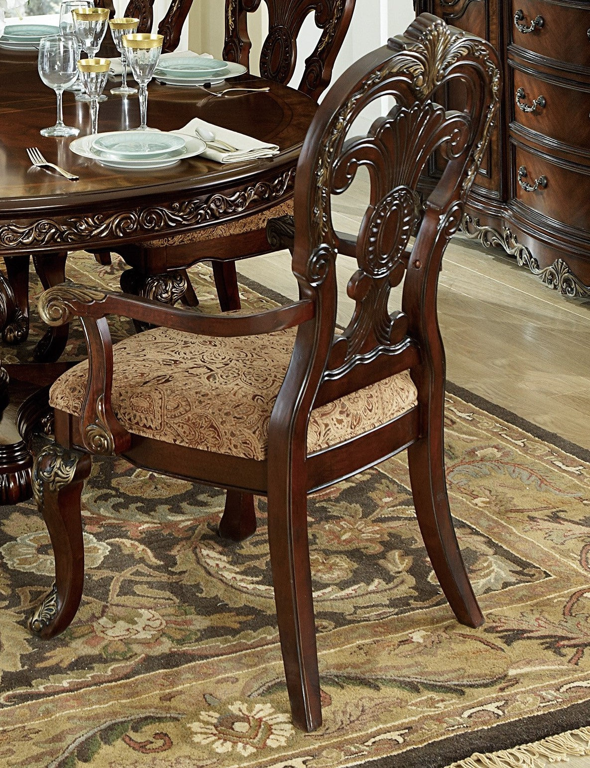 Ornate dark wood dining chair with upholstered paisley seat and gold accents