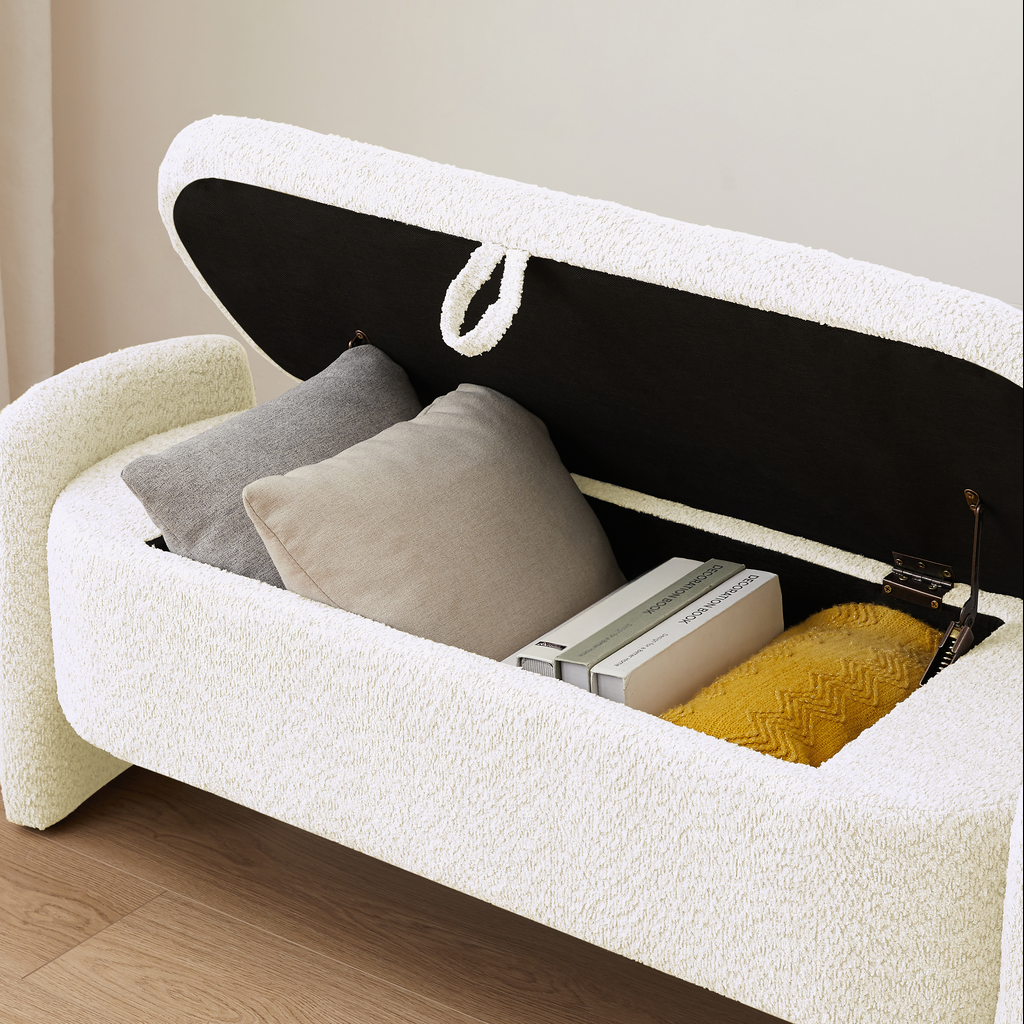 White boucle storage bench with open lid revealing pillows and yellow throw