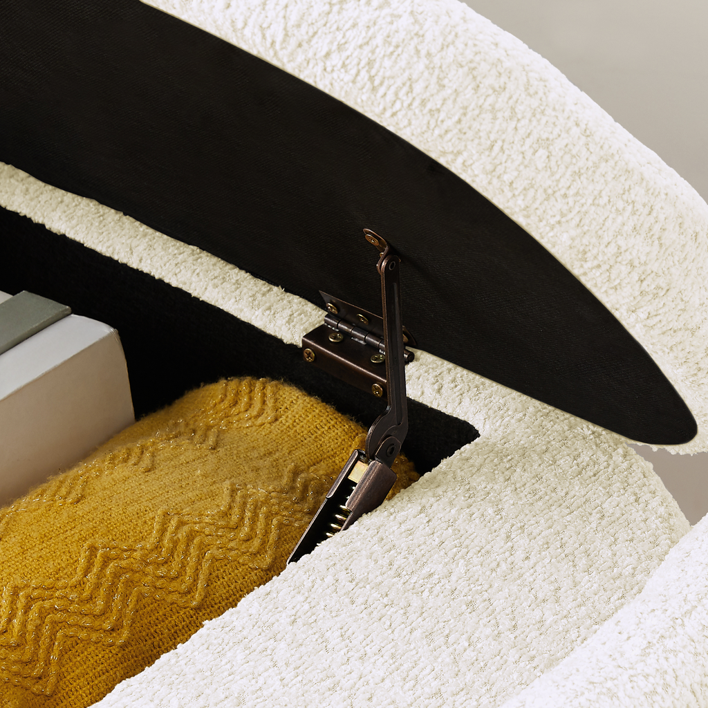 Cream boucle storage ottoman with open lid revealing yellow knit blanket