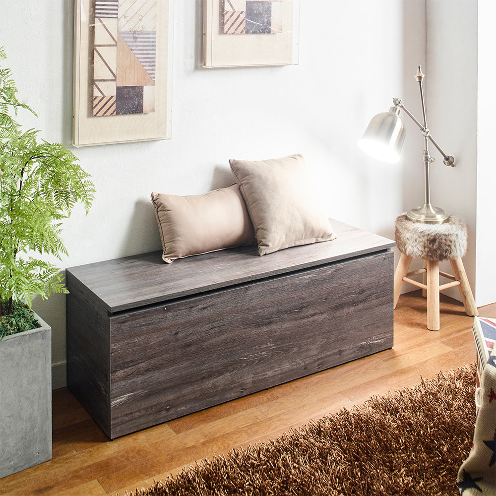 Dark wood storage bench with two taupe pillows on top