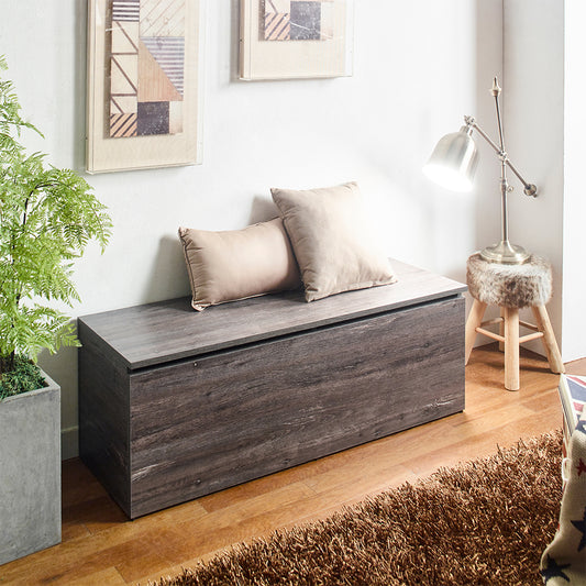 Dark wood storage bench with two taupe pillows on top
