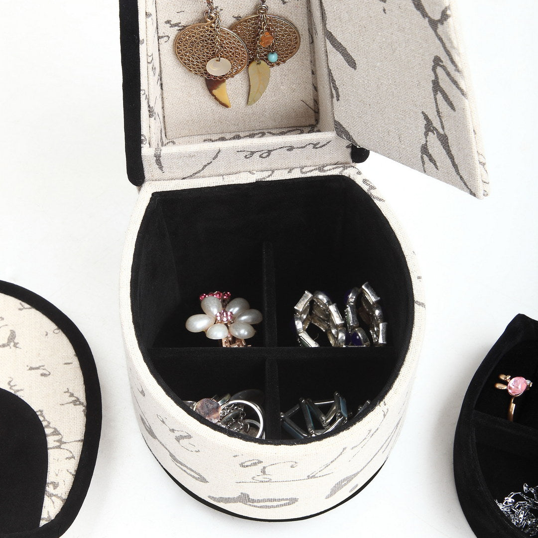 Elegant oval jewelry box with script pattern and black velvet lining holding rings and earrings