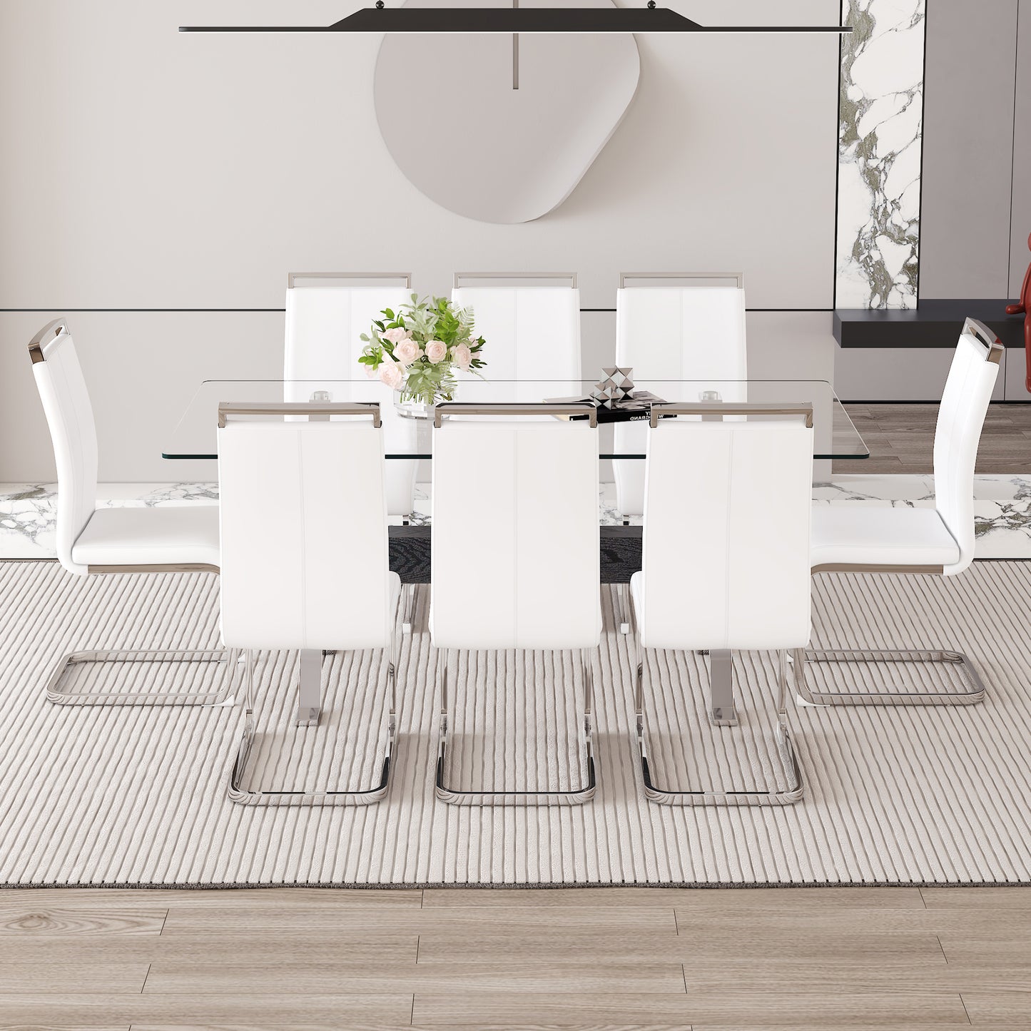 Six modern white leather dining chairs with chrome frames arranged around a glasstop table