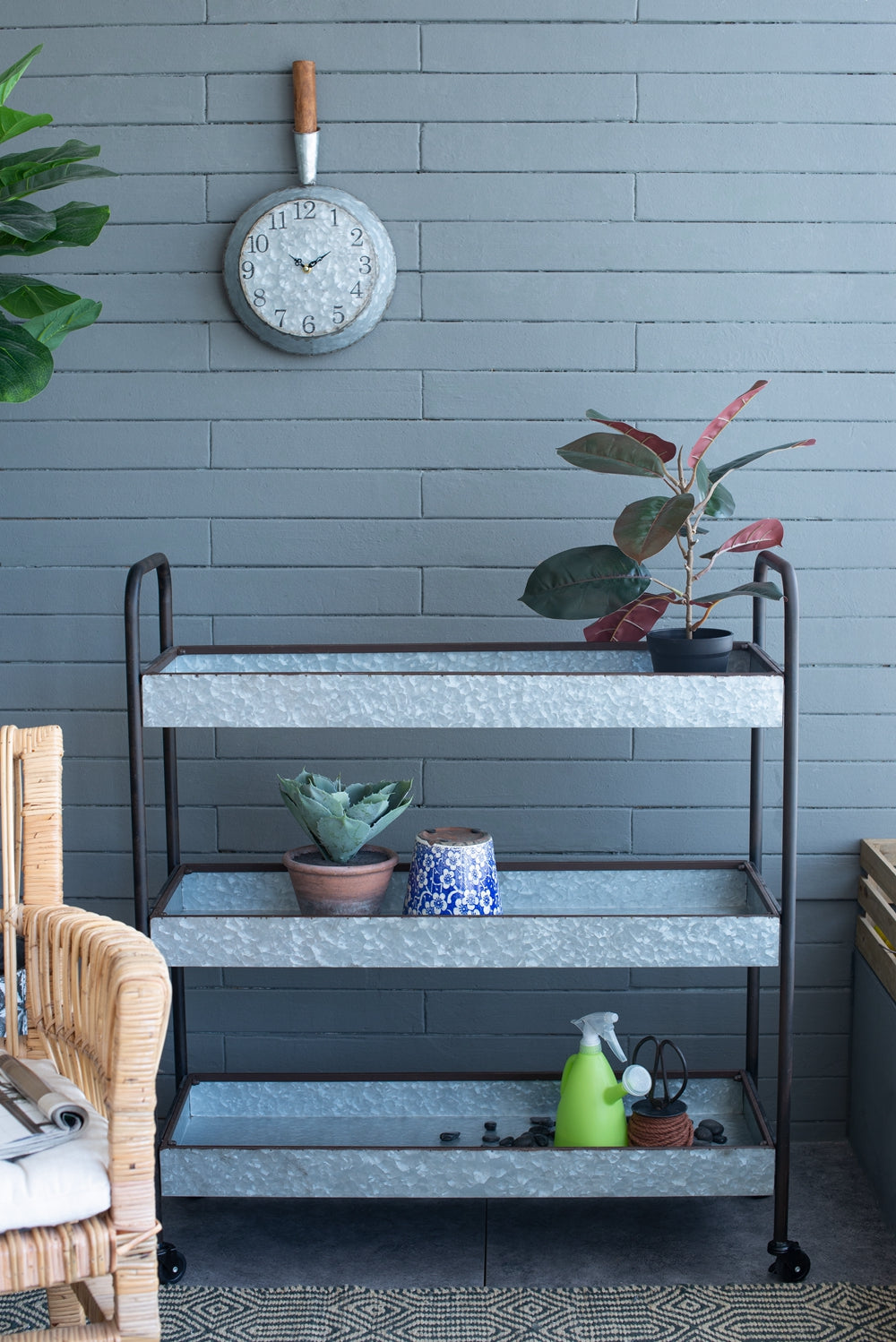 Galvanized metal tiered plant stand with black frame holding various potted plants and gardening tools