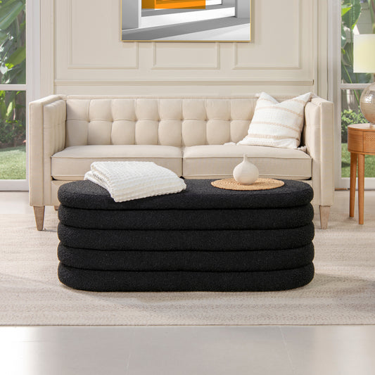Black oval textured ottoman with a woven tray and white vase