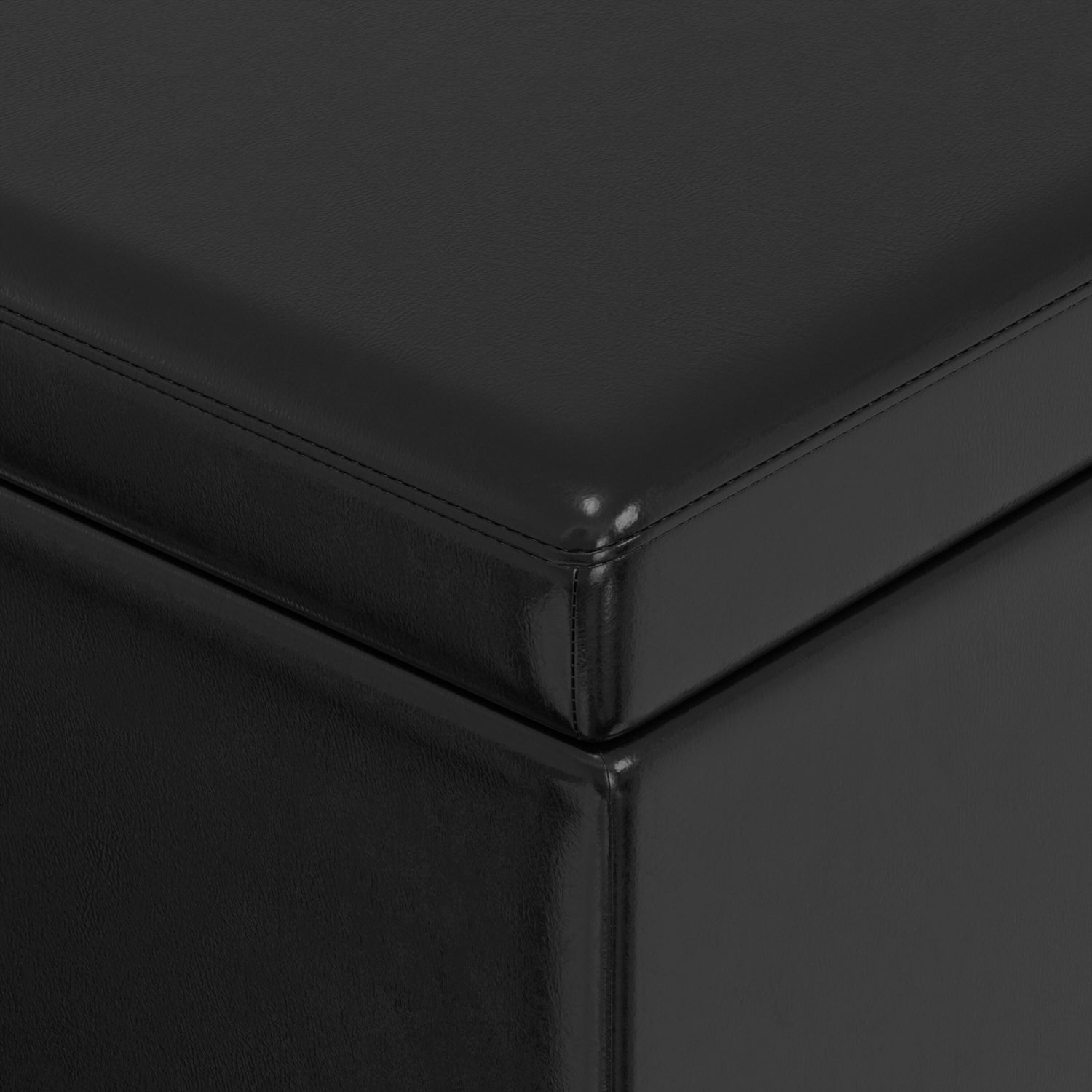Black faux leather storage ottoman corner detail with precise stitching