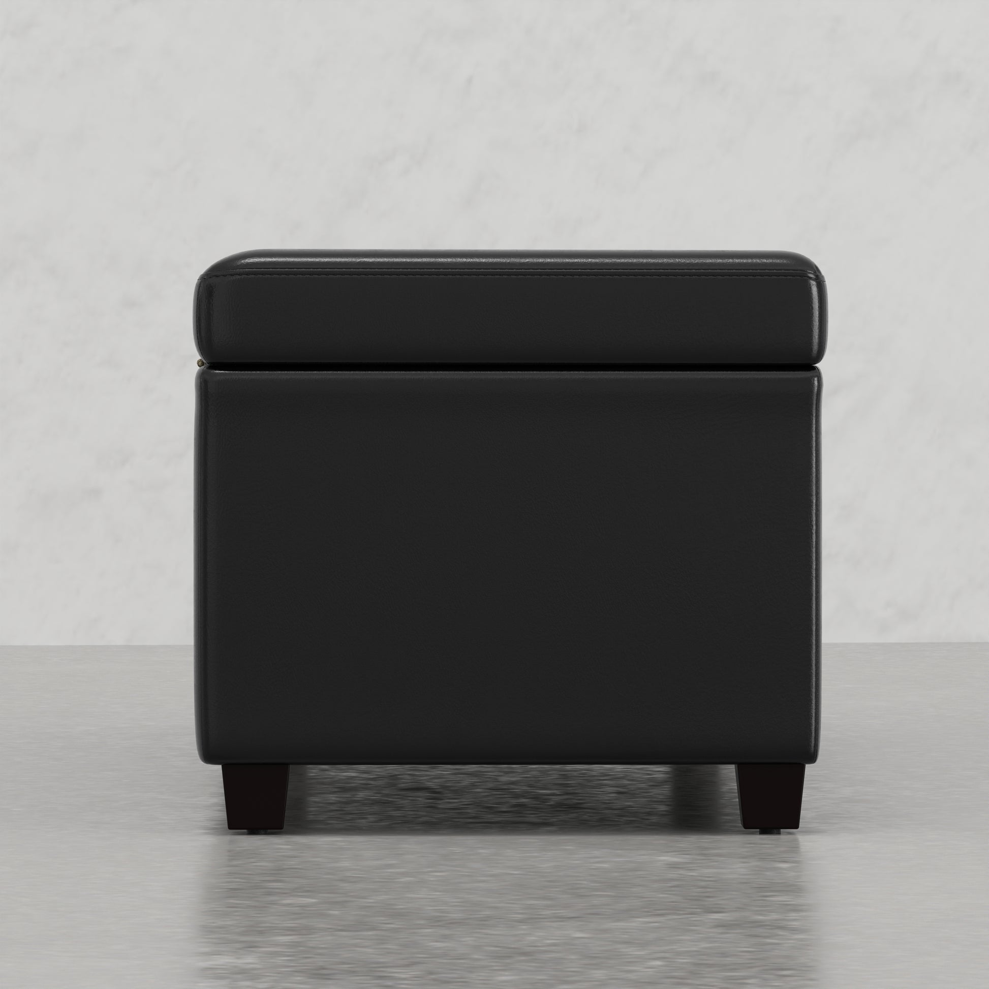 Black faux leather storage ottoman with tufted lid and dark wood legs