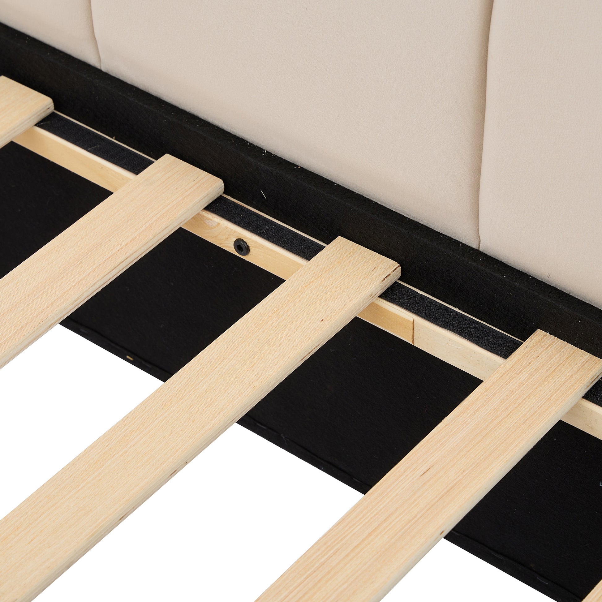 Closeup of beige upholstered headboard and wooden slats on a bed frame