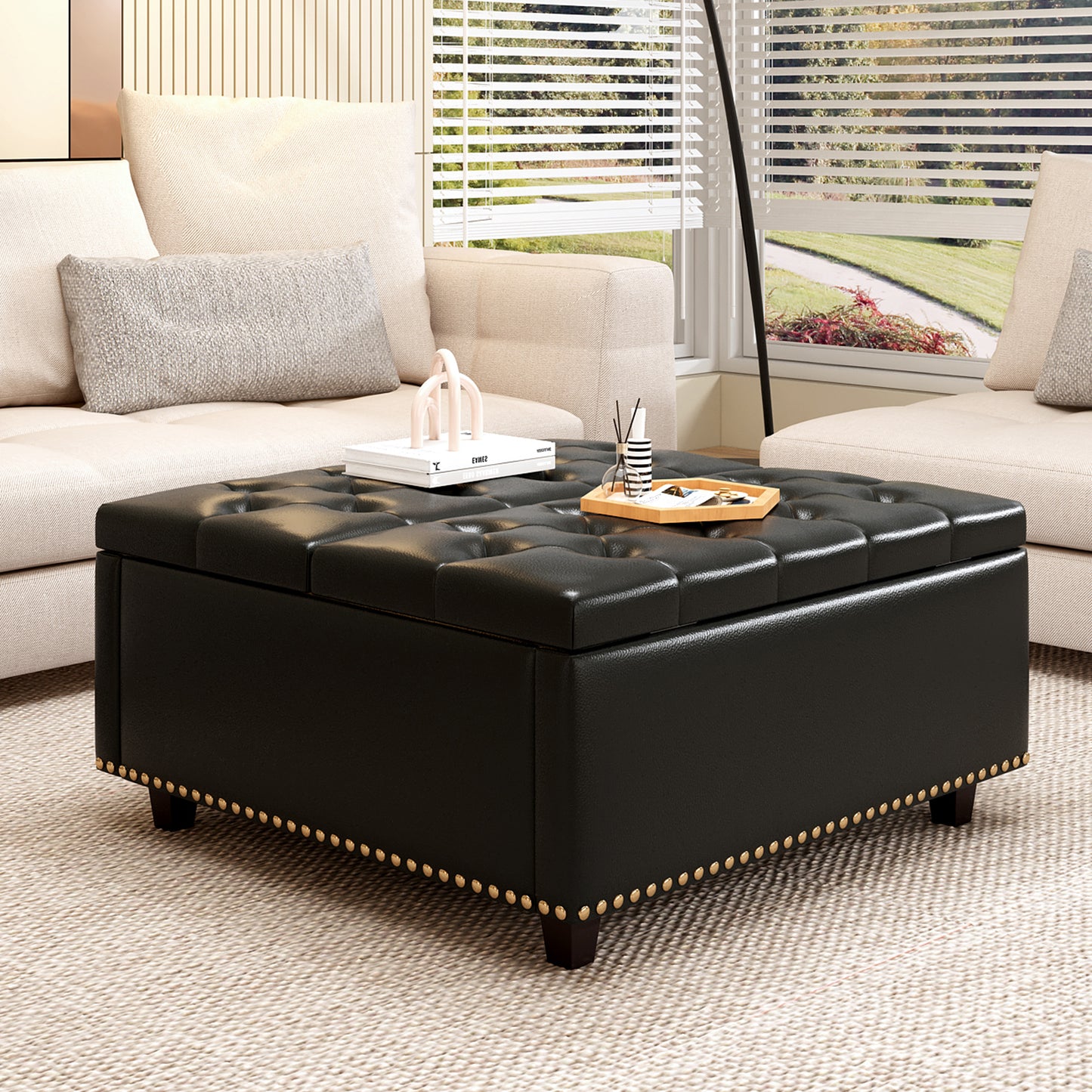 Tufted black faux leather storage ottoman with antique brass nailhead trim