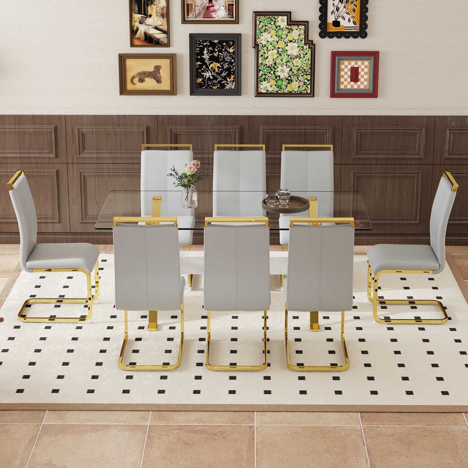 Six grey faux leather dining chairs with gold metal frames around a glasstop table
