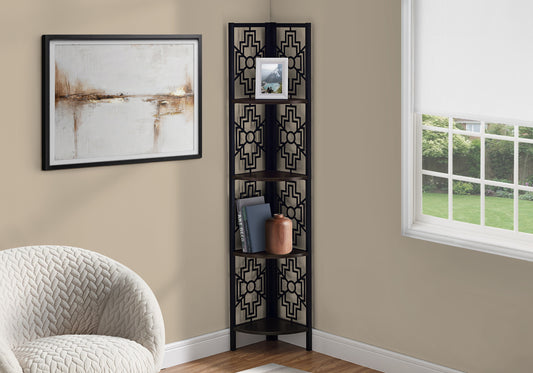 Black corner shelf with geometric cutouts holding books and a vase
