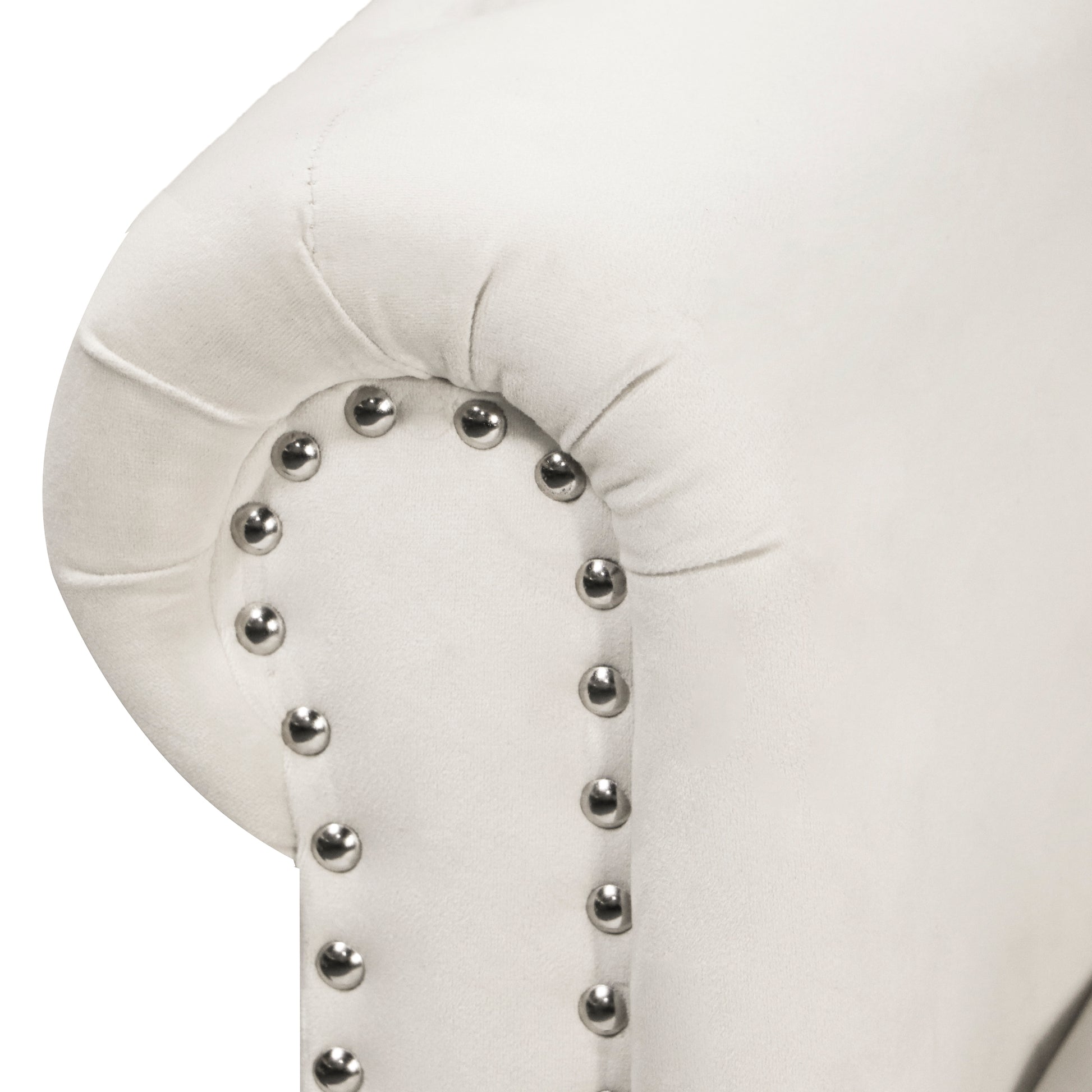 Closeup of a cream velvet sofa arm with decorative silver nailhead trim