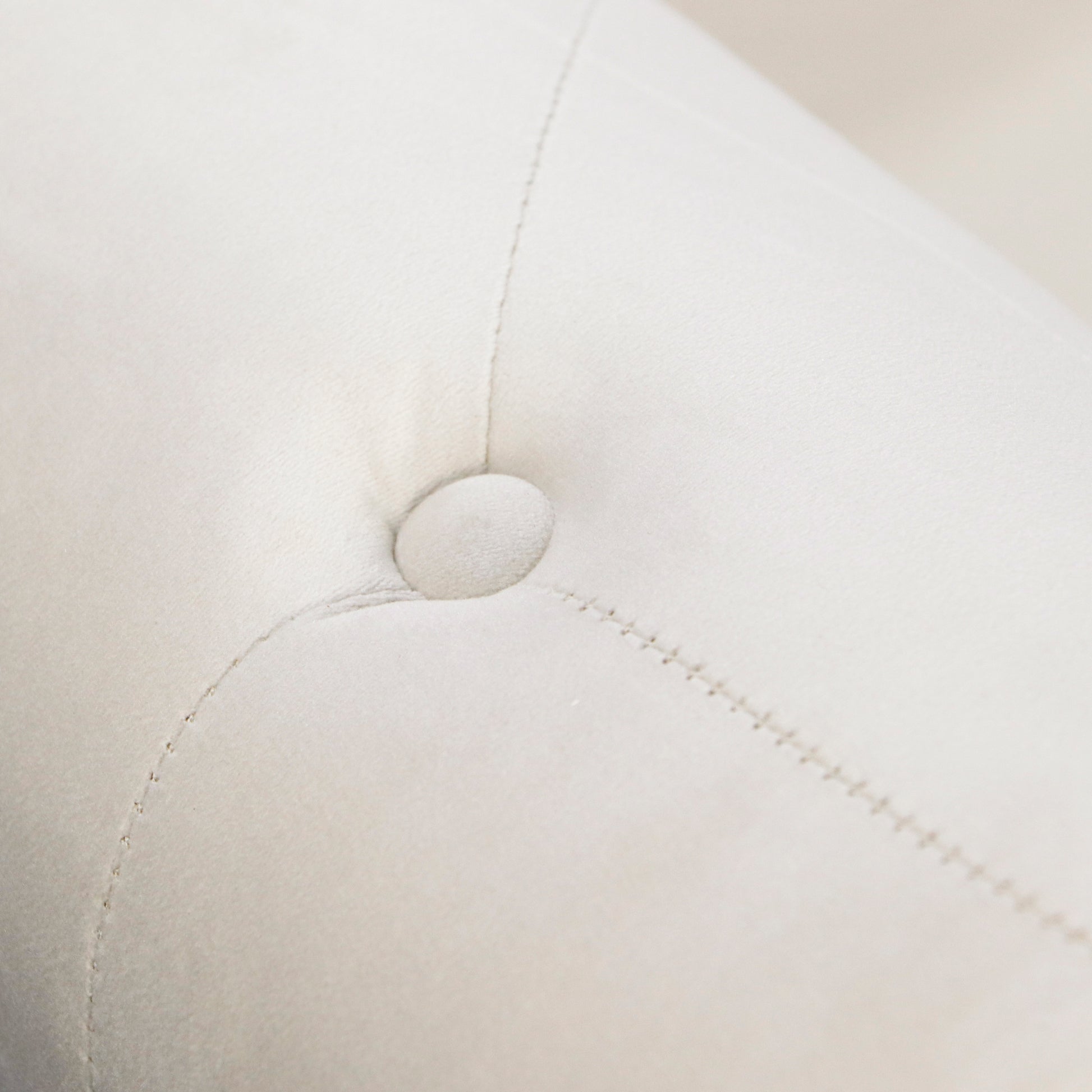 Closeup of tufted ivory velvet upholstery with button detail