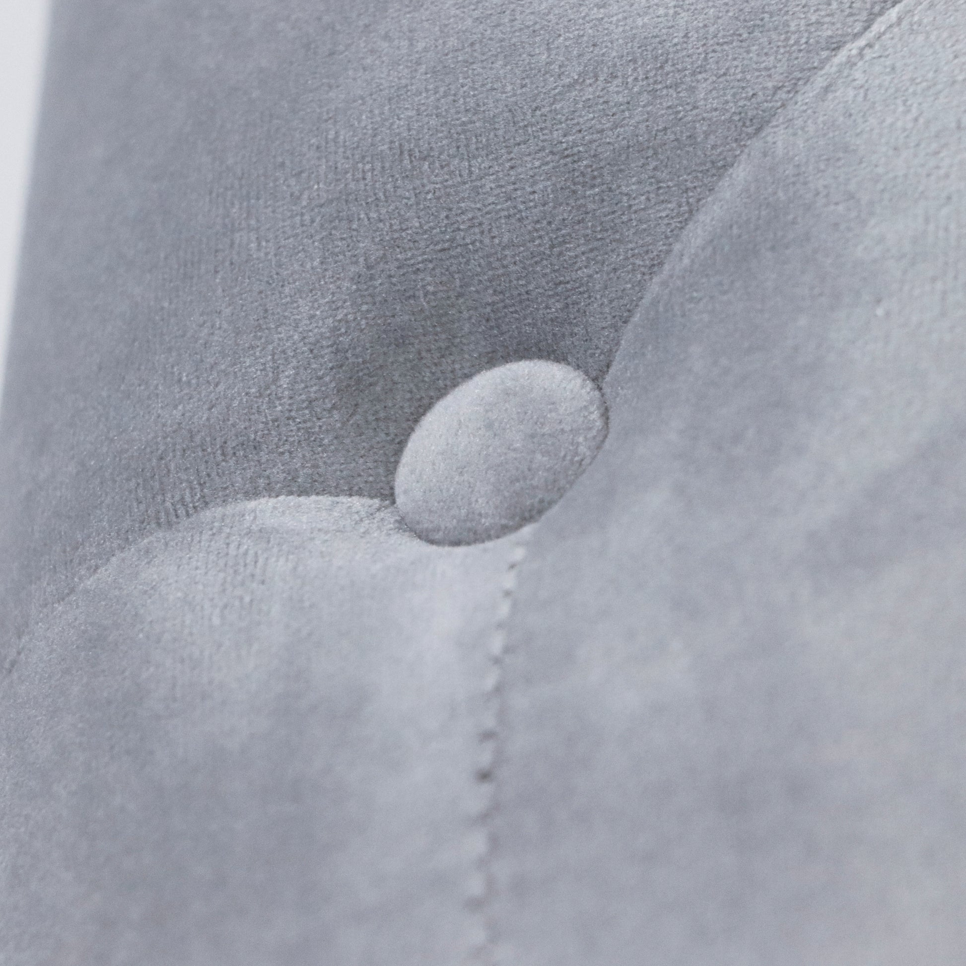 Close up of tufted grey velvet fabric with button detail