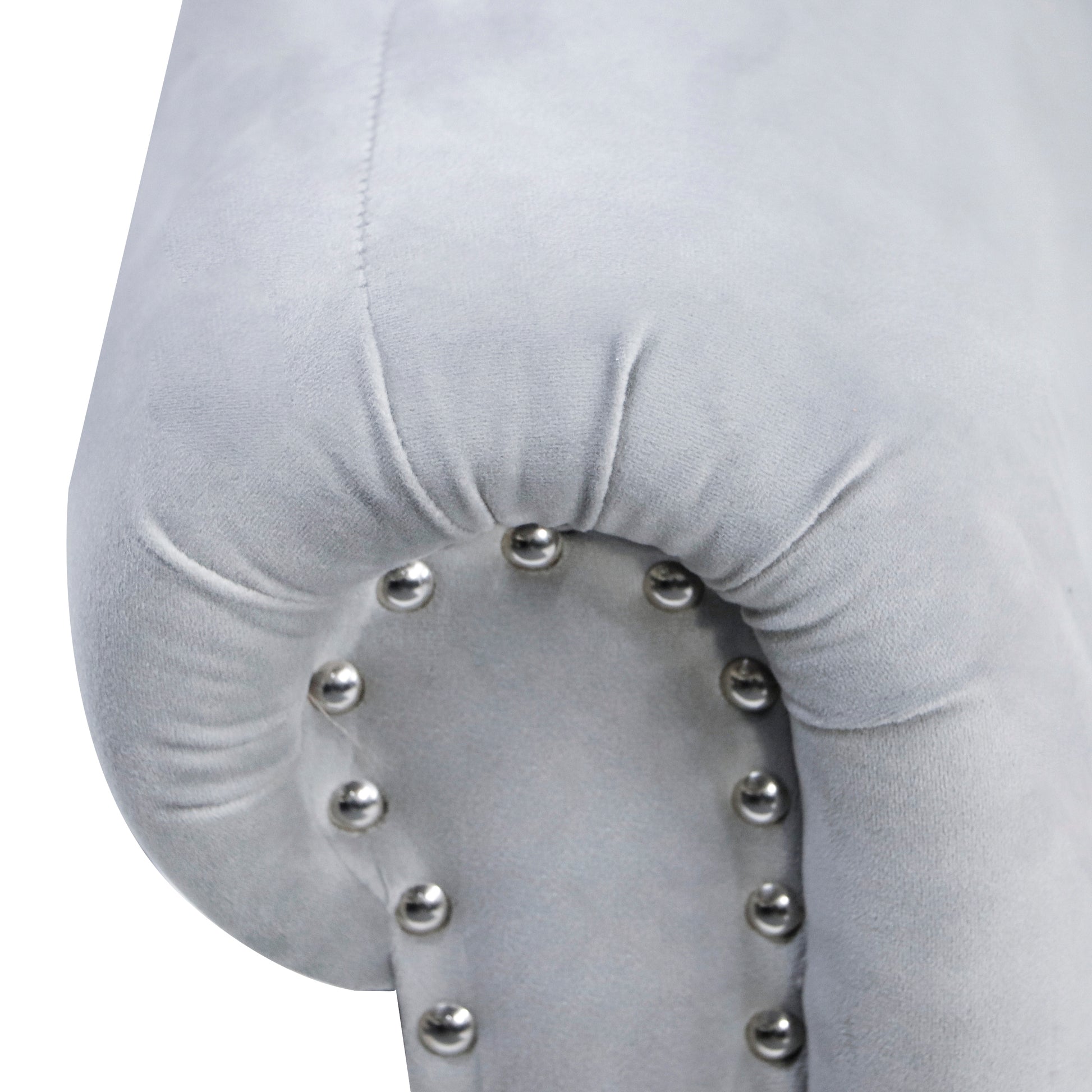 Light gray velvet armchair detail with tufted accents and silver nailhead trim