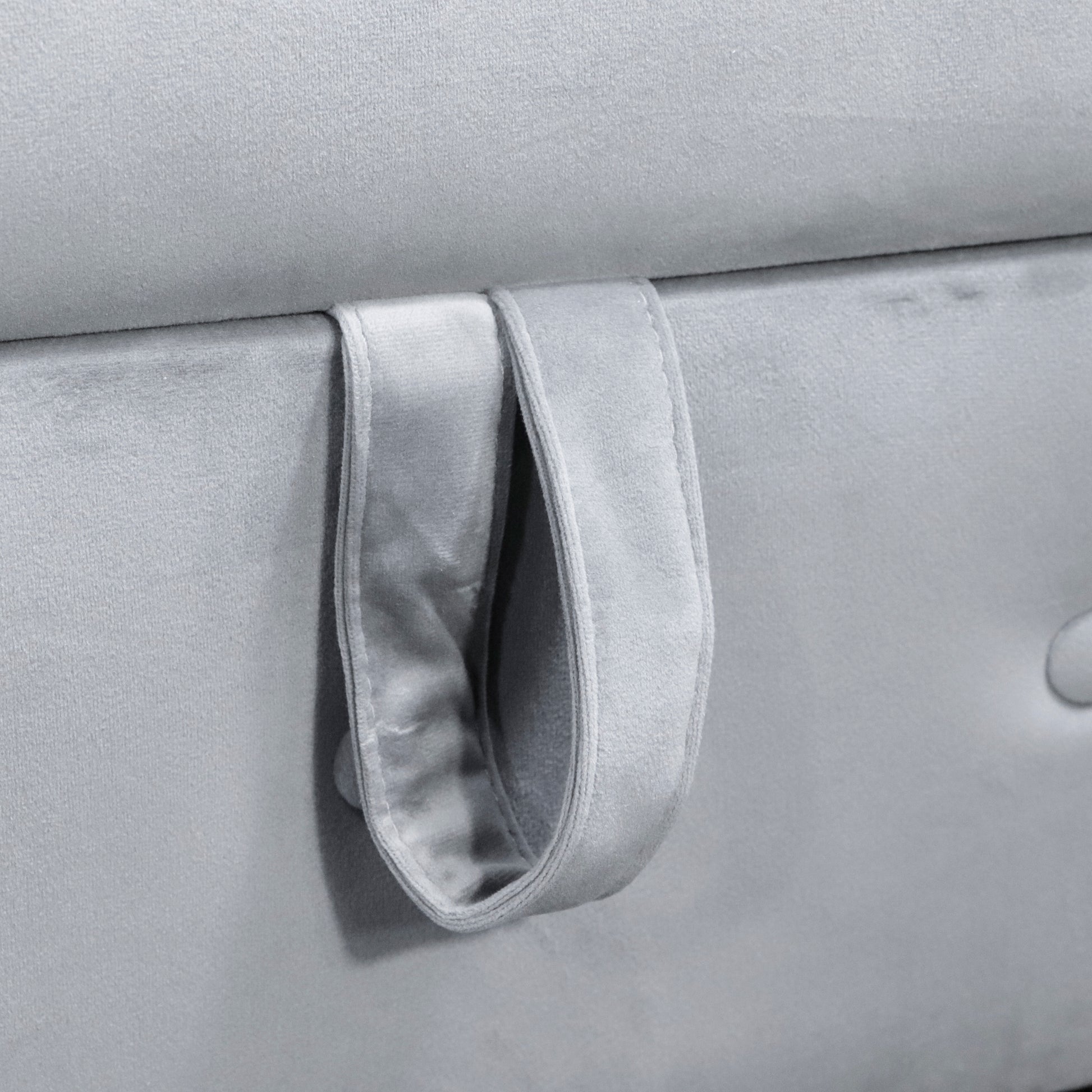 Closeup of grey velvet fabric storage ottoman with attached fabric pull tab