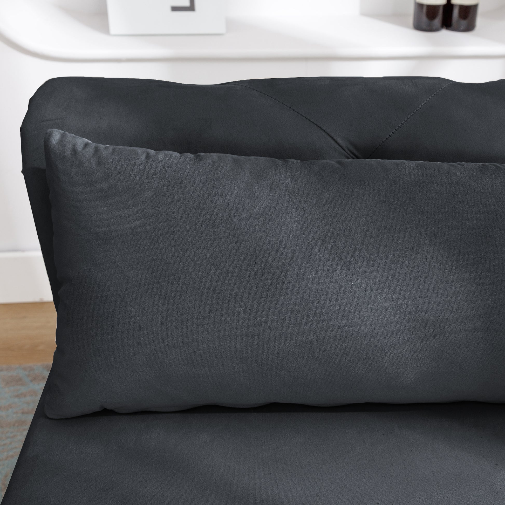 Dark gray velvet couch with plush throw pillow