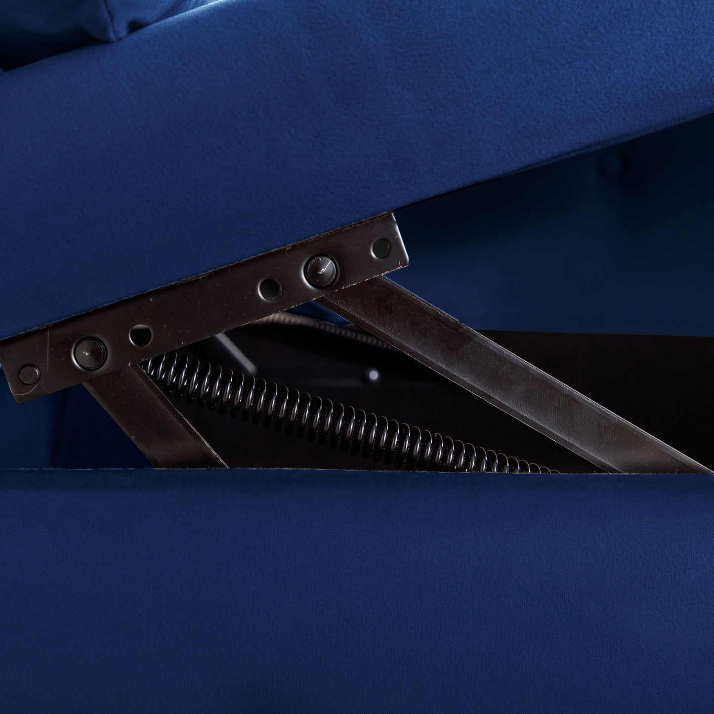 Closeup of blue velvet sofa storage mechanism with metal spring