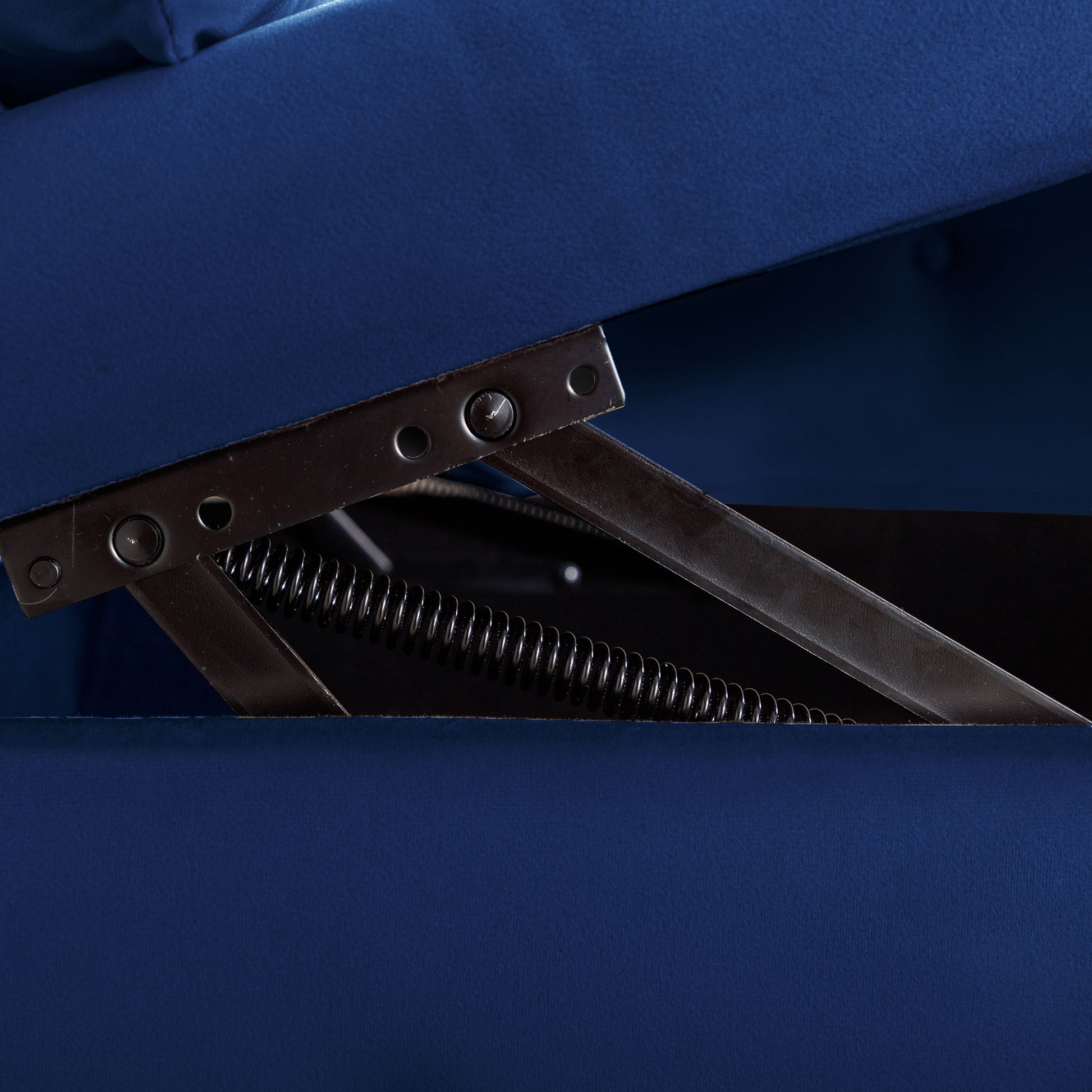 Closeup of blue velvet sofa storage mechanism with metal spring