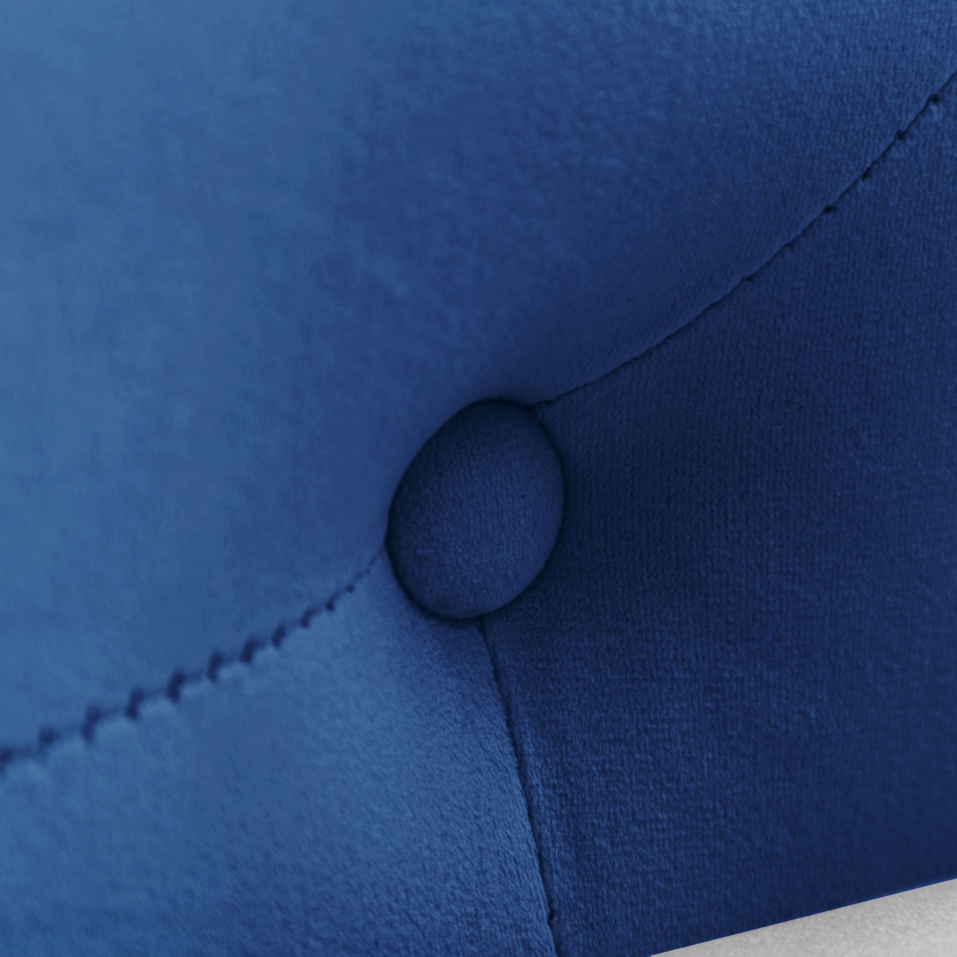 Closeup of tufted sapphire blue velvet fabric with button detail