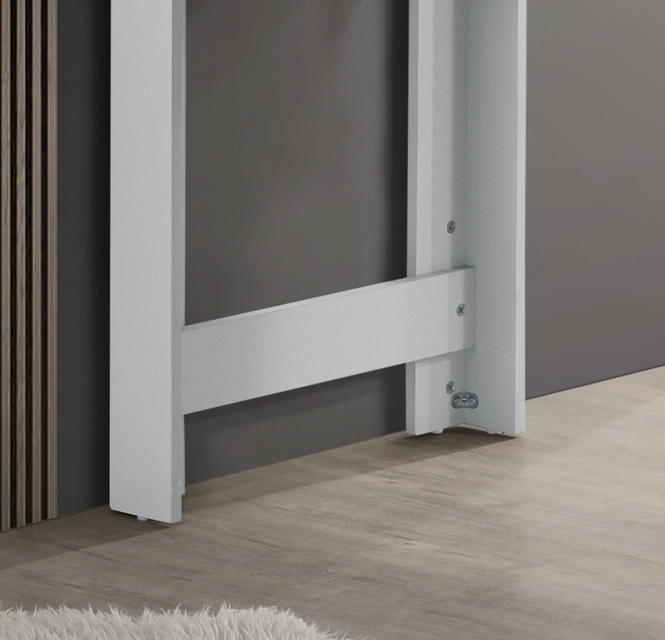 White metal bed frame support leg detail on wood floor