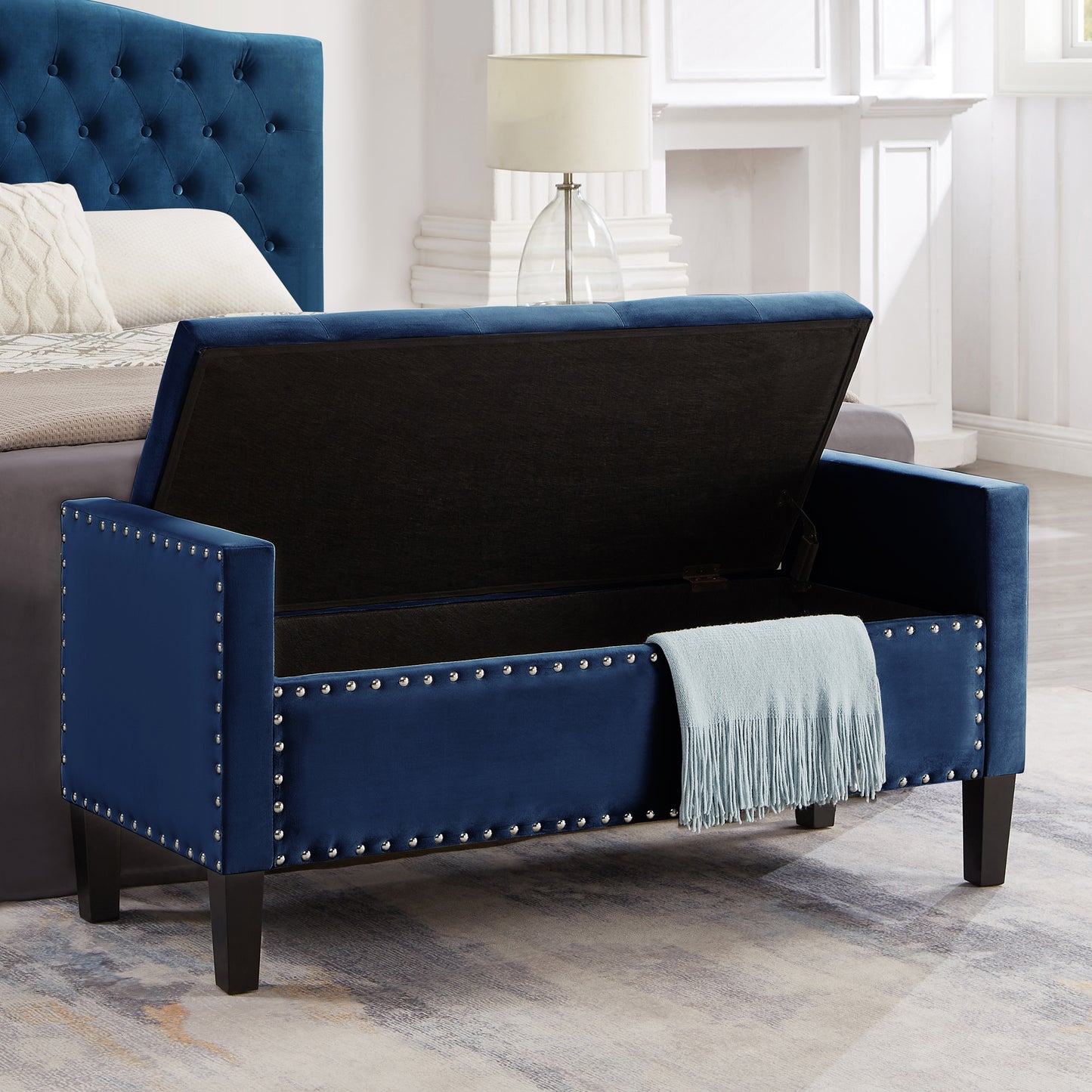 Navy blue velvet storage bench with silver nailhead trim and a light blue throw