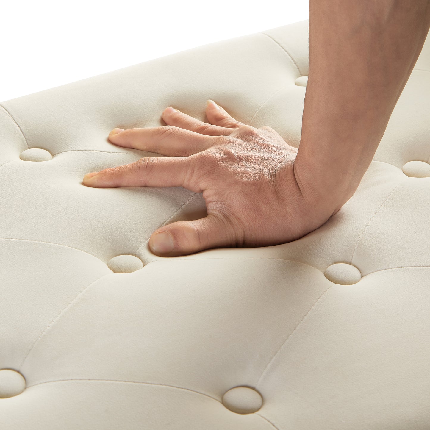 Cream tufted ottoman detail with hand pressing into soft upholstery
