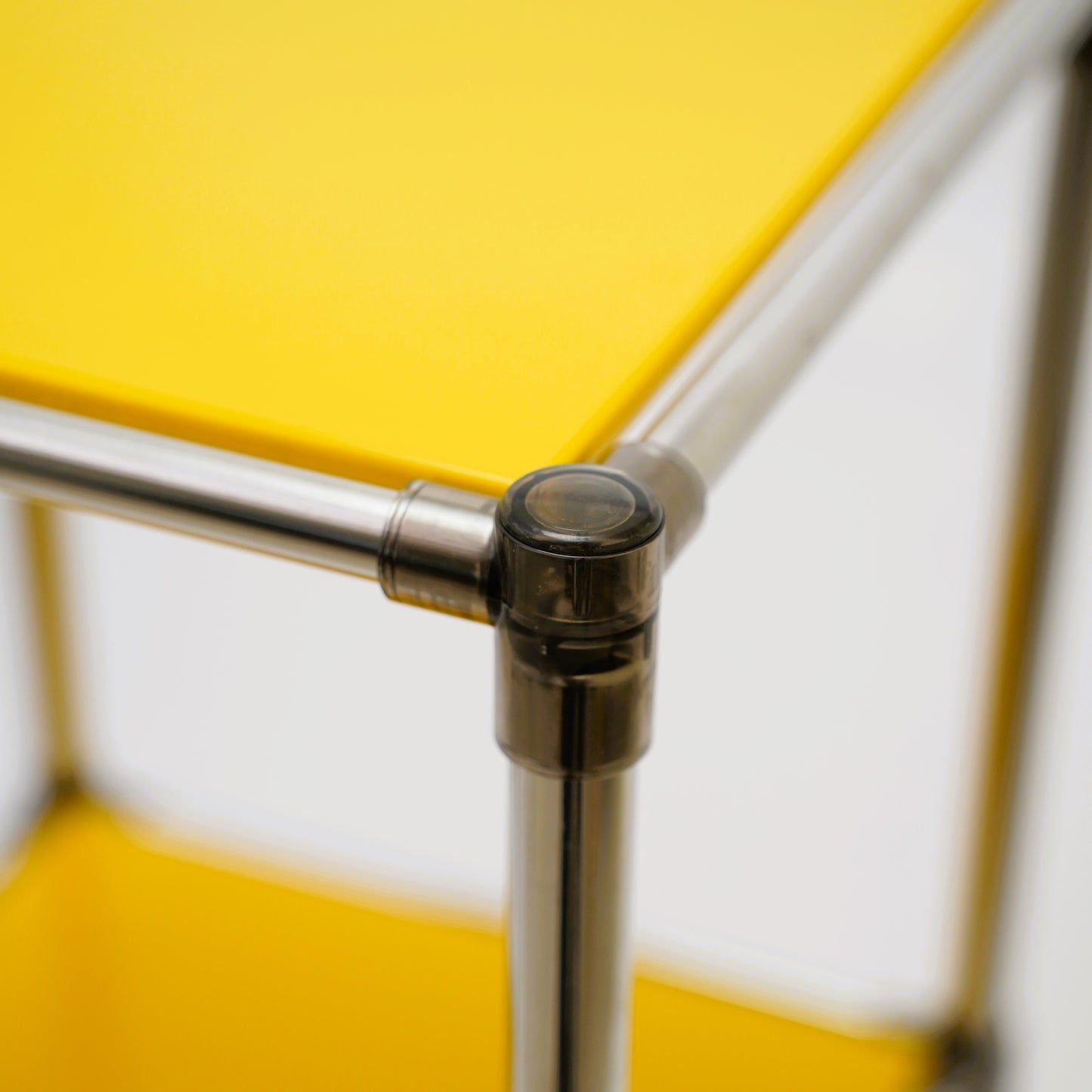 Yellow modular shelving unit corner with silver metal poles and clear connectors
