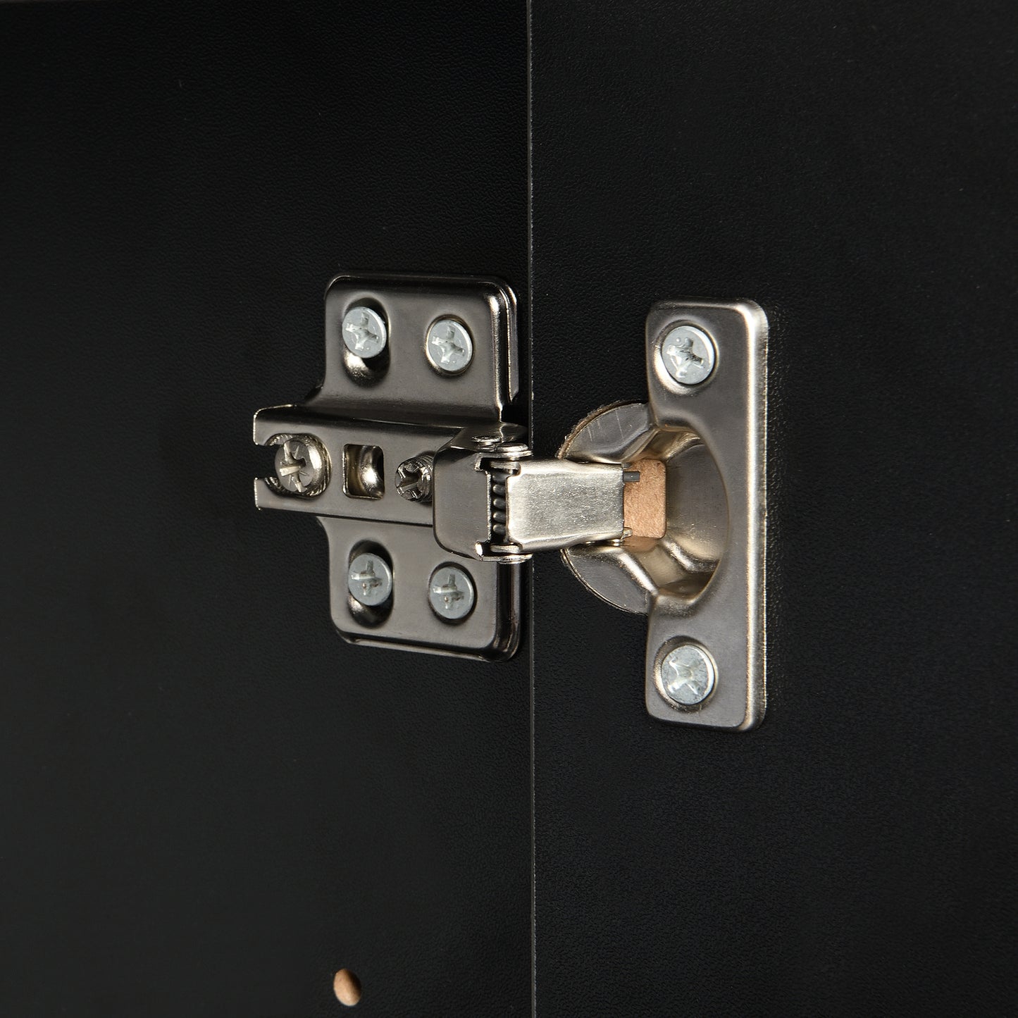 Closeup of silver metal cabinet hinge on black textured surface