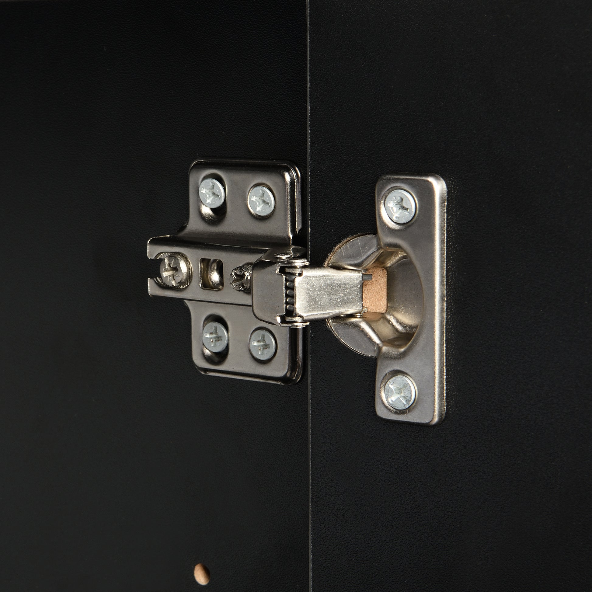 Closeup of silver metal cabinet hinge on black textured surface