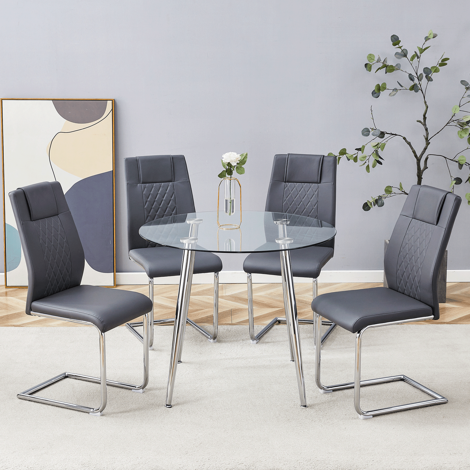 Round glass top dining table with chrome legs and four grey faux leather chairs