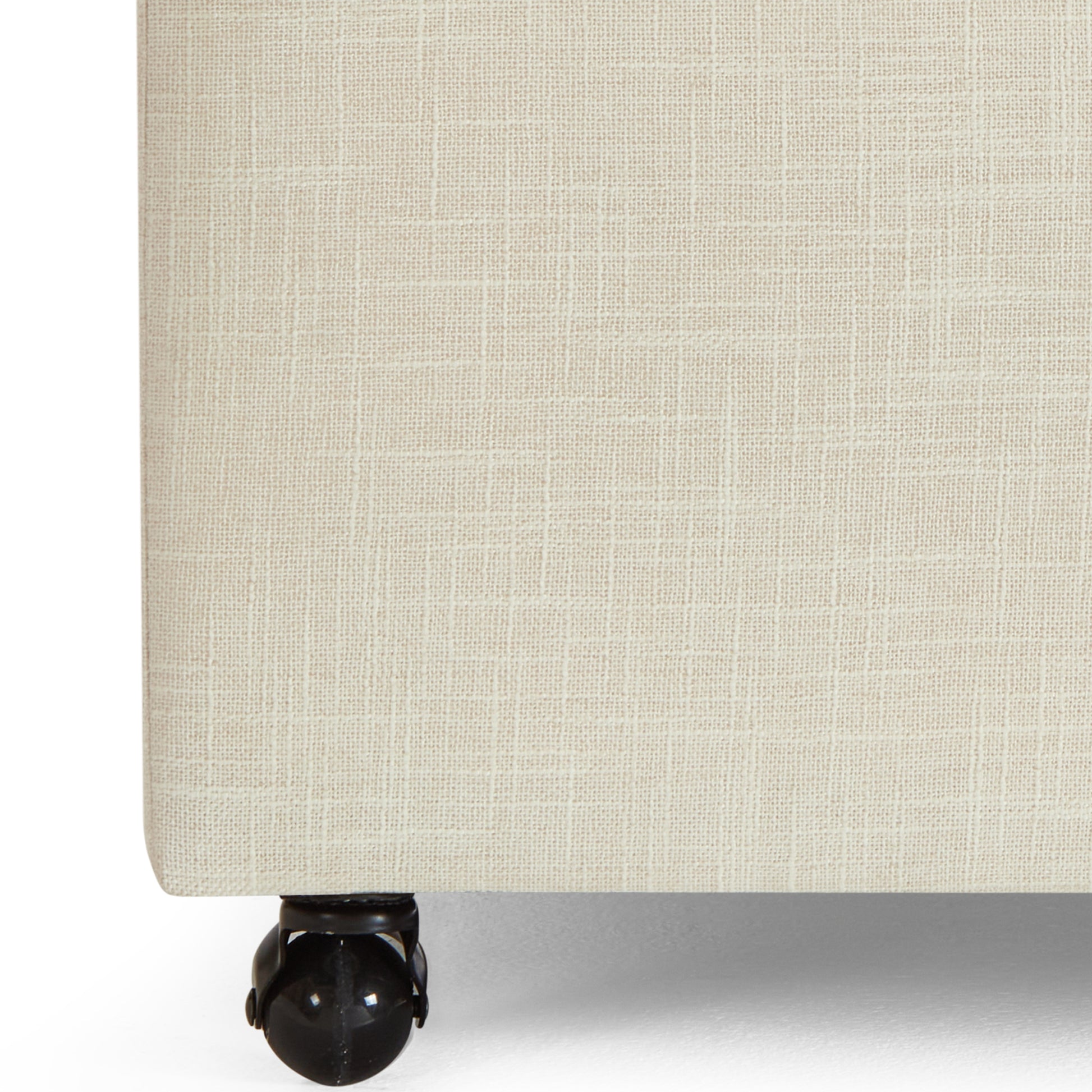 Beige linen upholstered ottoman with black caster wheels
