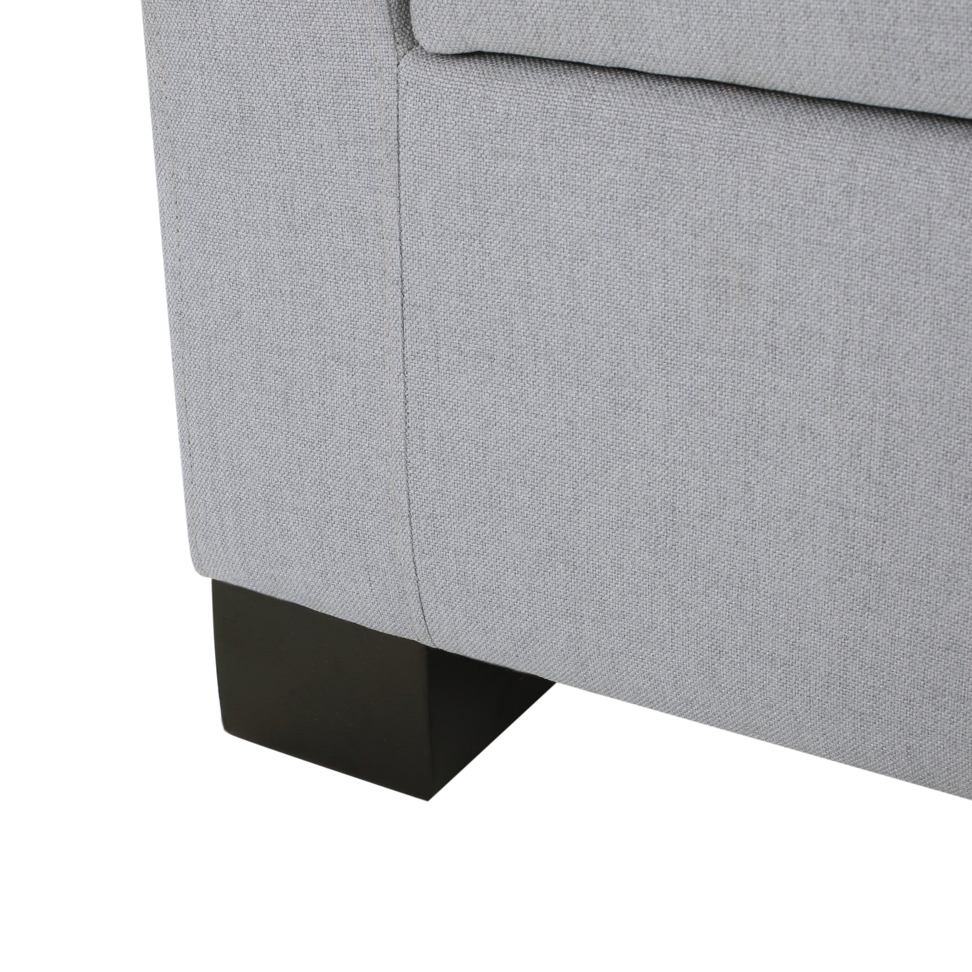 Closeup of a grey fabric sofa corner with a dark wood leg