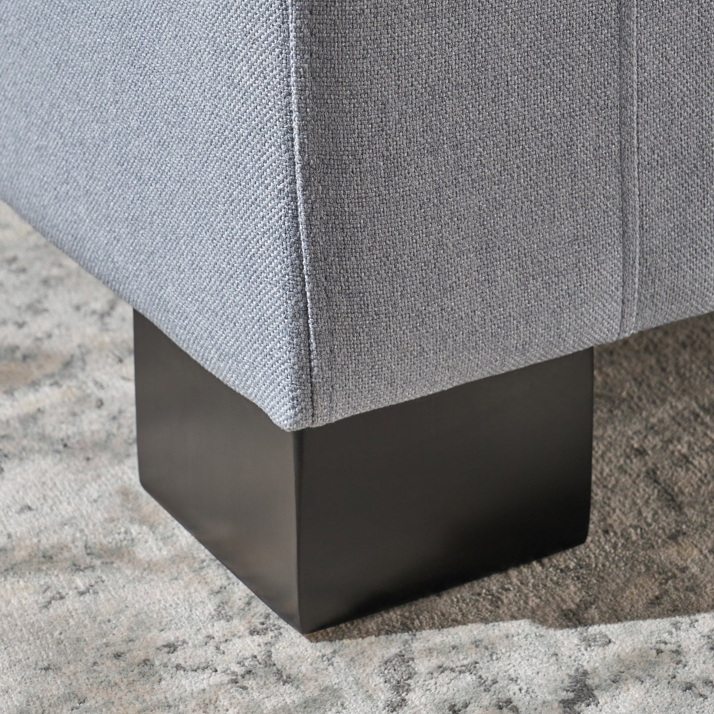 Light blue fabric armchair detail with square black wooden leg