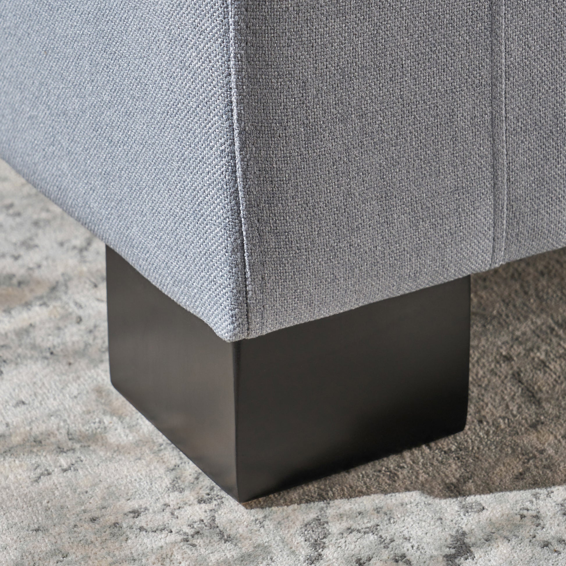 Light blue fabric armchair detail with square black wooden leg
