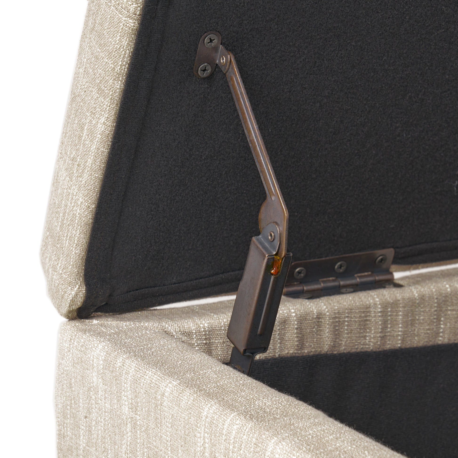 Closeup of beige linen upholstered storage ottoman hinge mechanism