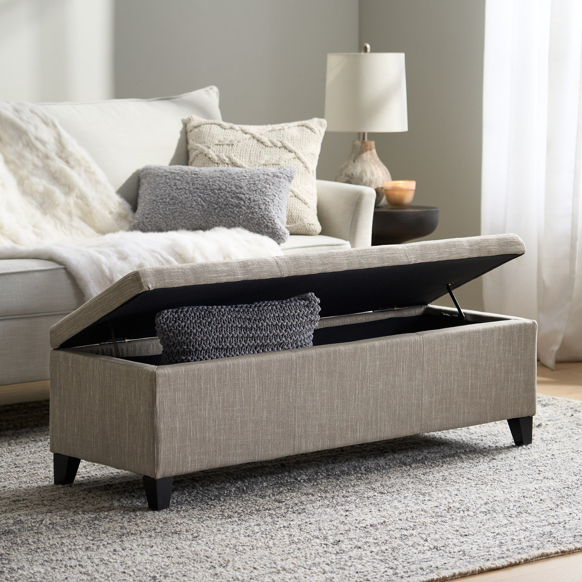 Beige fabric storage ottoman with dark legs